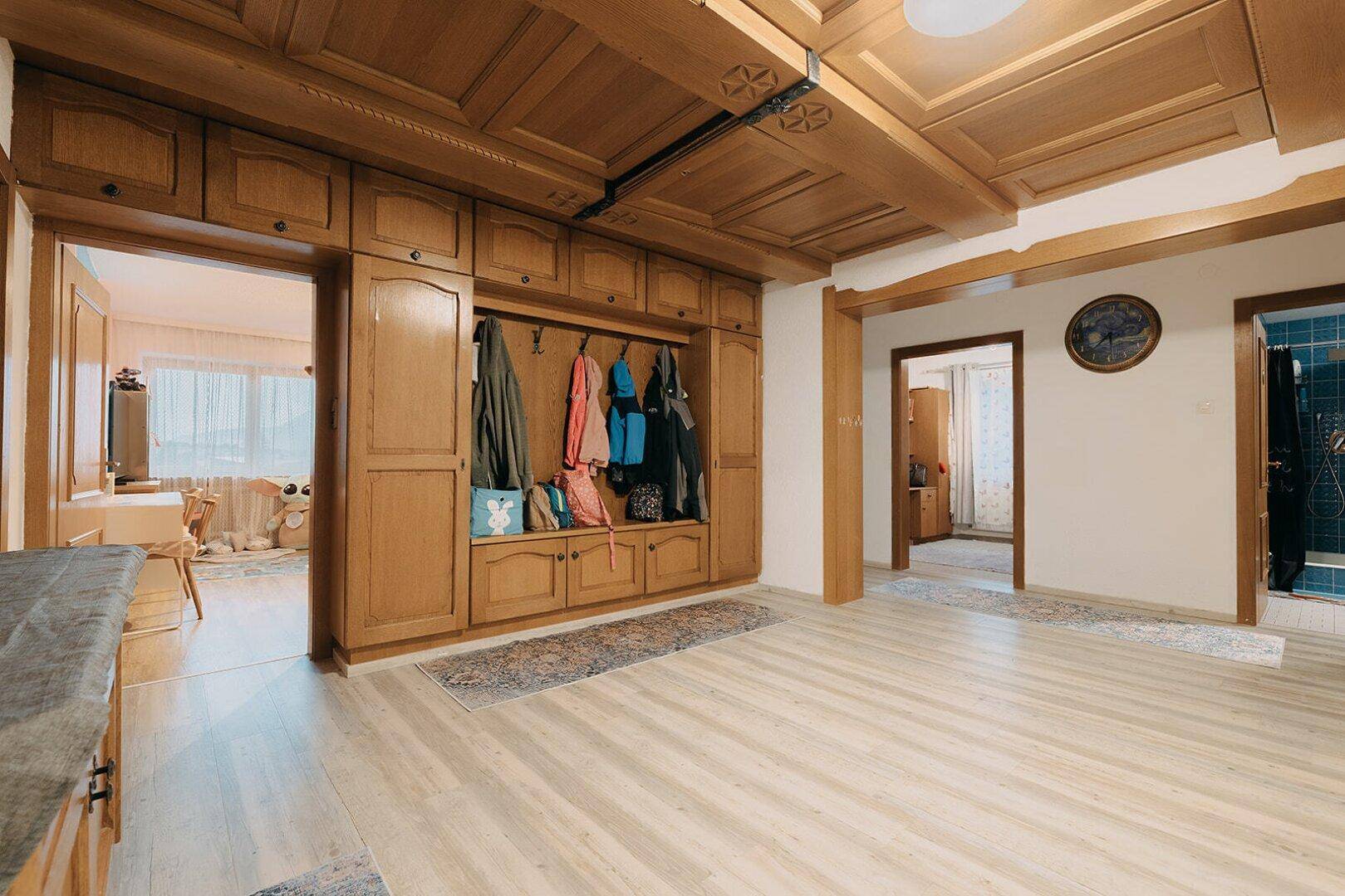 Geräumiger Flur mit Holzboden, Einbauschränken und Zugang zu weiteren Räumen.