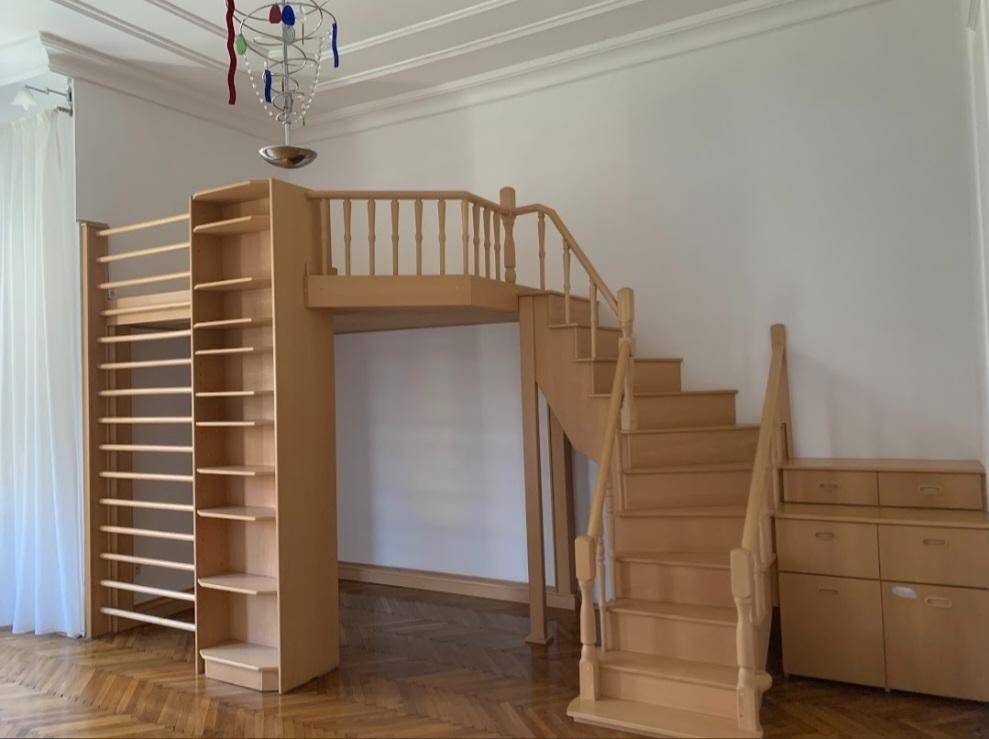Detailansicht des maßgefertigten Holzhochbetts mit Treppe und integriertem Bücherregal im Schlafzimmer.