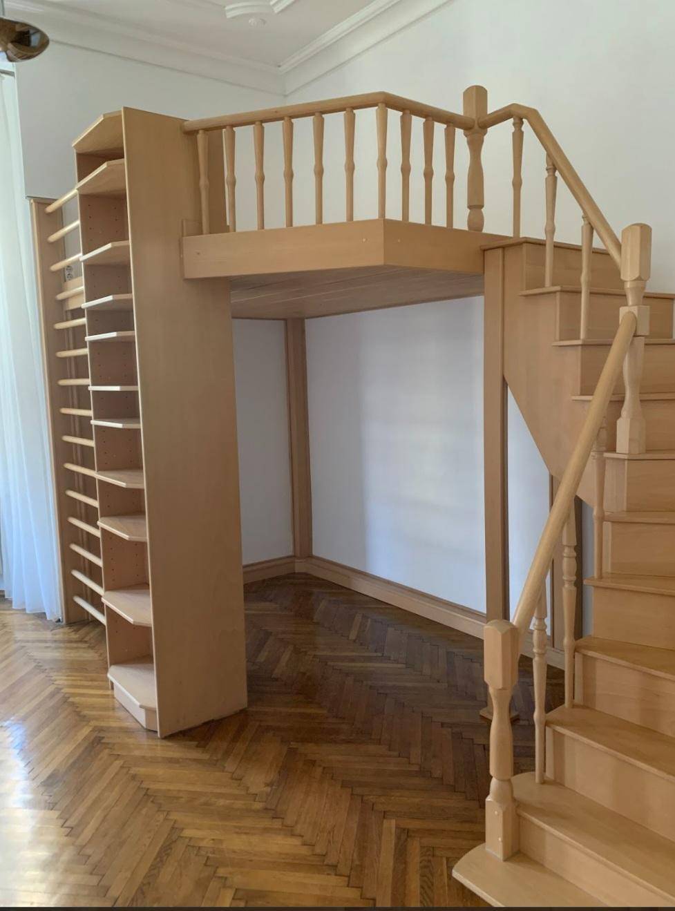 Blick auf das Holzhochbett mit Treppenzugang und dem darunterliegenden Bereich im hellen Zimmer.