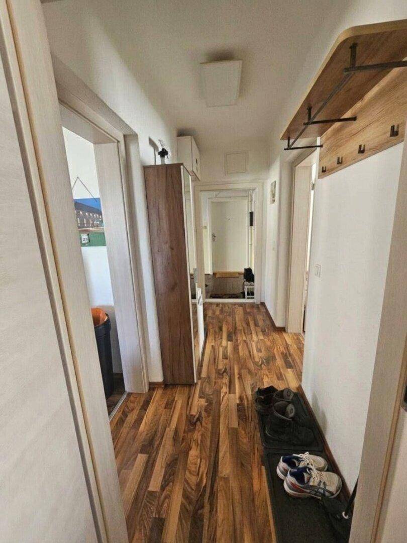 Heller Flur mit Holzoptik-Laminatboden und einer Garderobe für Mäntel und Schuhe.