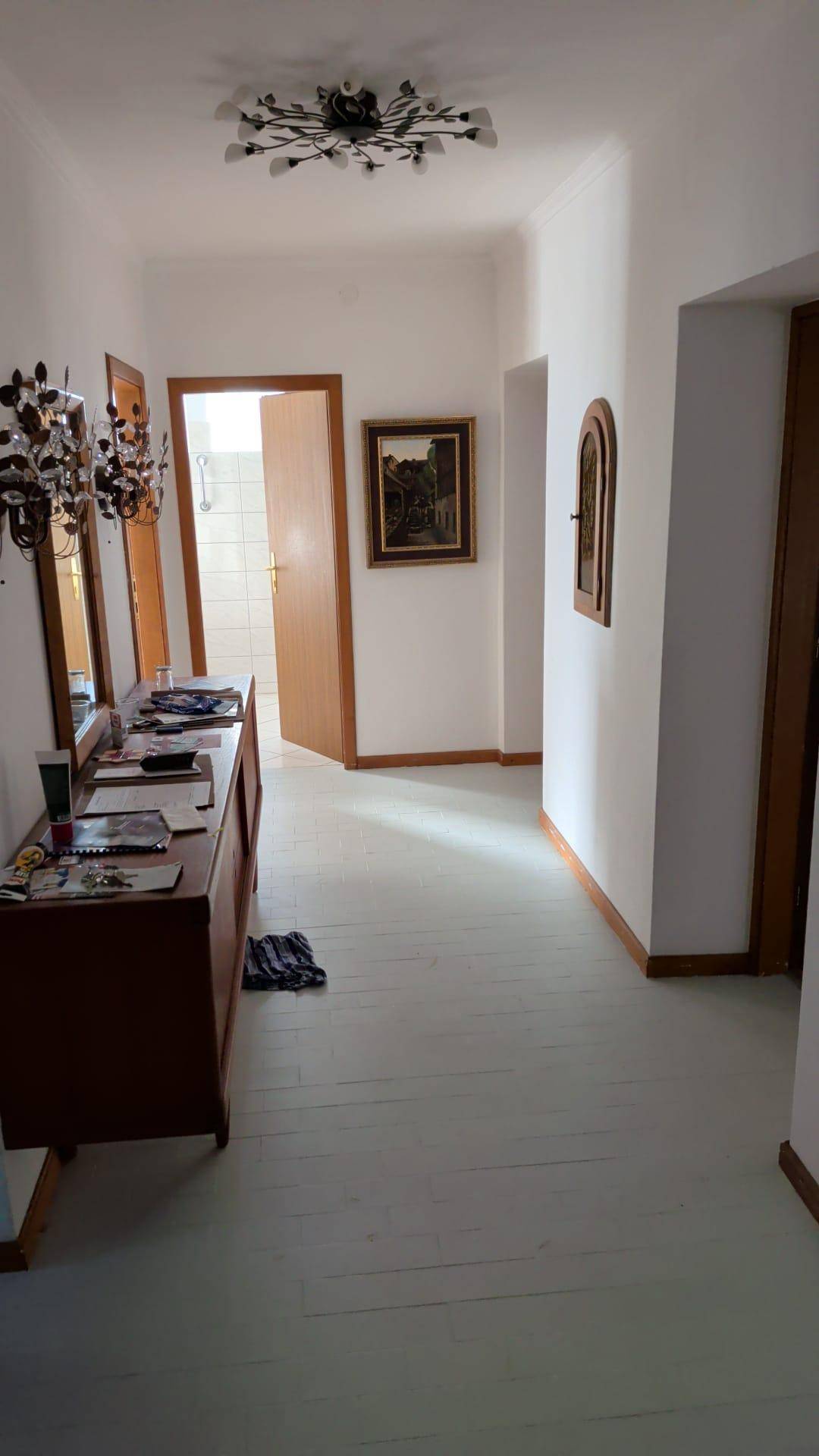 Heller Flur mit Holzboden, Spiegel und einer Kommode, die Stauraum bietet.