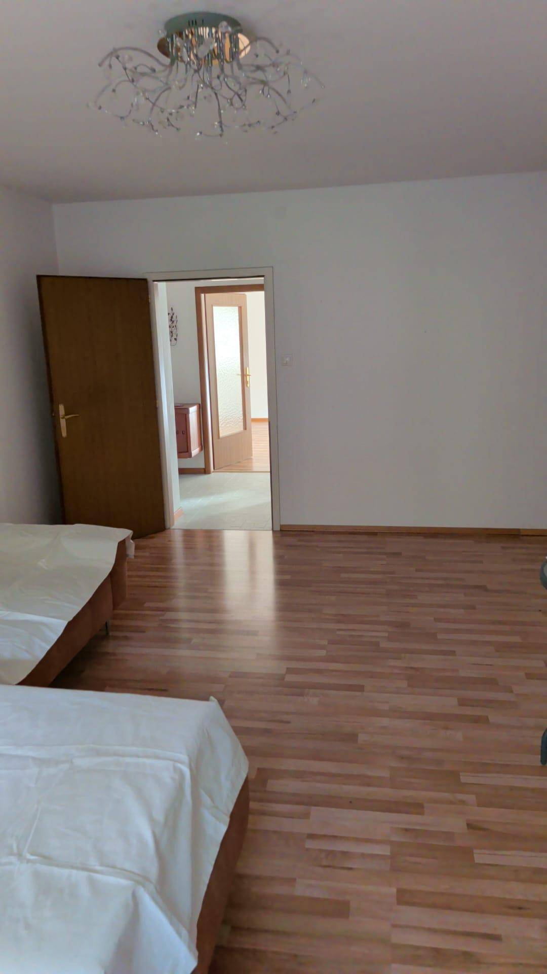 Geräumiges Schlafzimmer mit Parkettboden und Zugang zu weiteren Räumen.