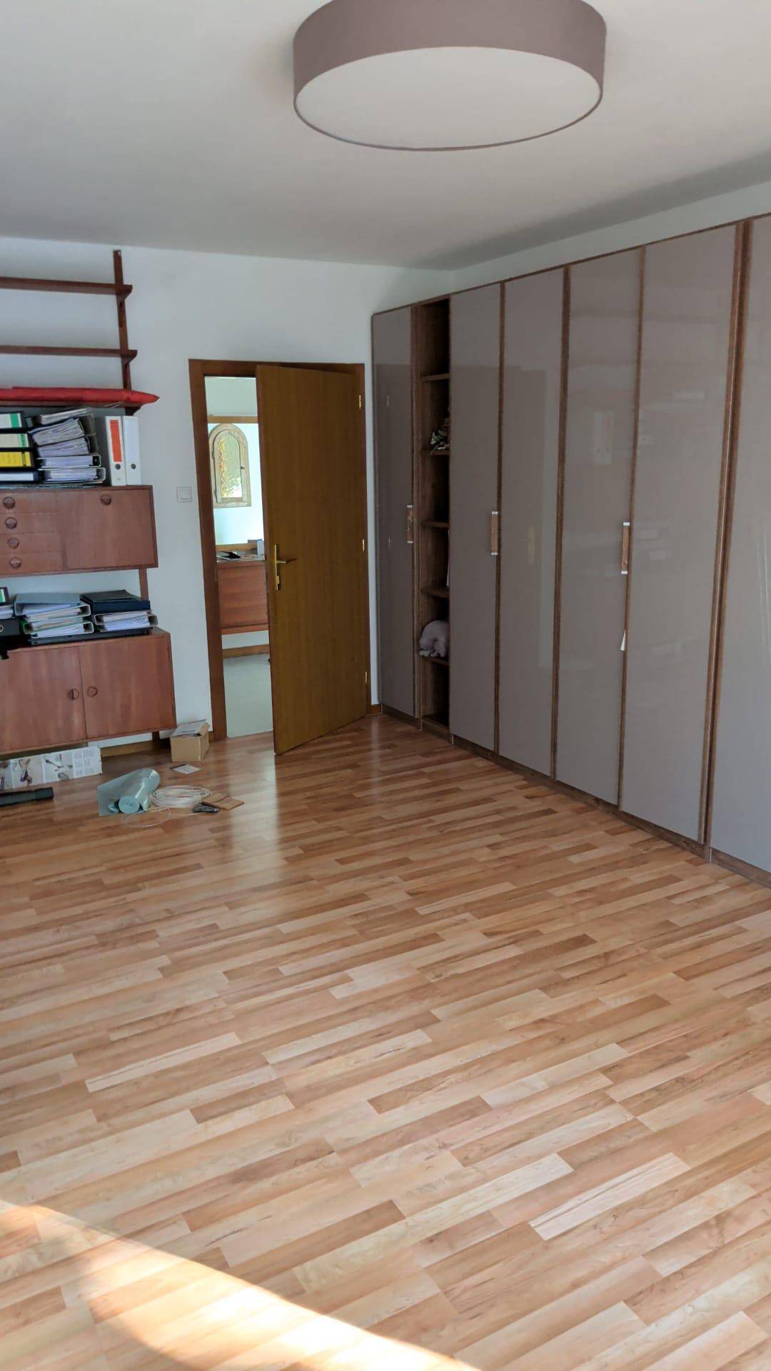 Schlafzimmer mit Parkettboden, Einbauschränken und Regalen für zusätzlichen Stauraum.