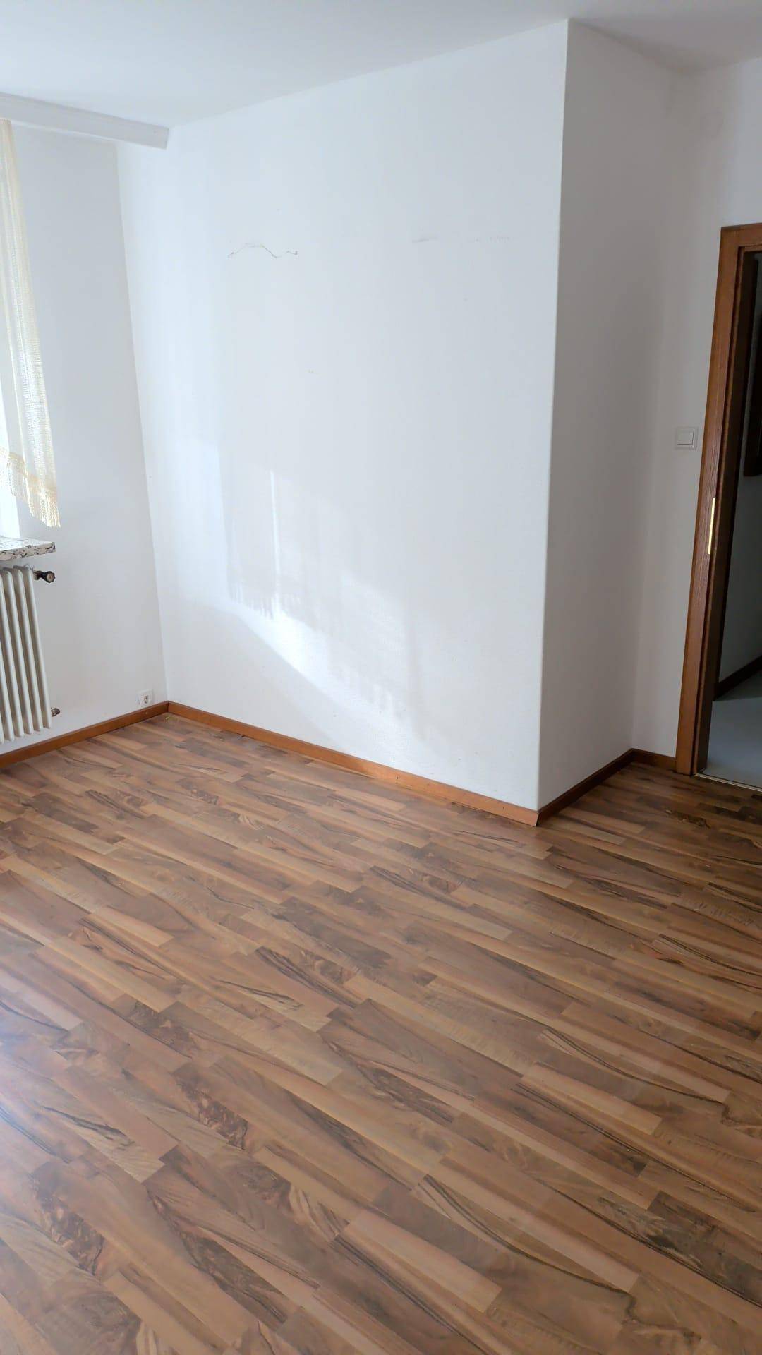 Geräumiger Wohnraum mit Parkettboden und weißen Wänden, bereit zur individuellen Gestaltung.