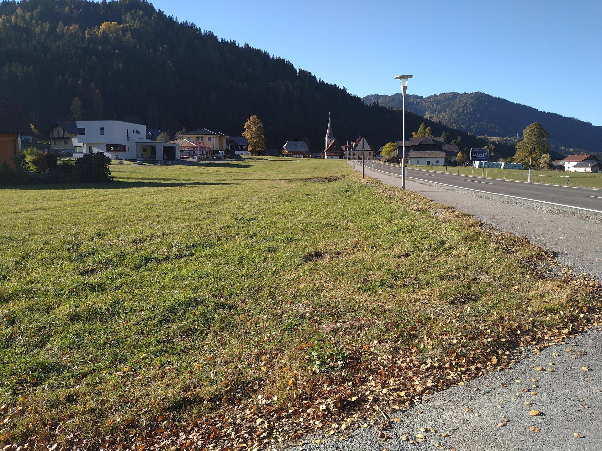 Weitläufiges Grundstück mit Blick auf die umliegende Berglandschaft und Dorfbebauung.