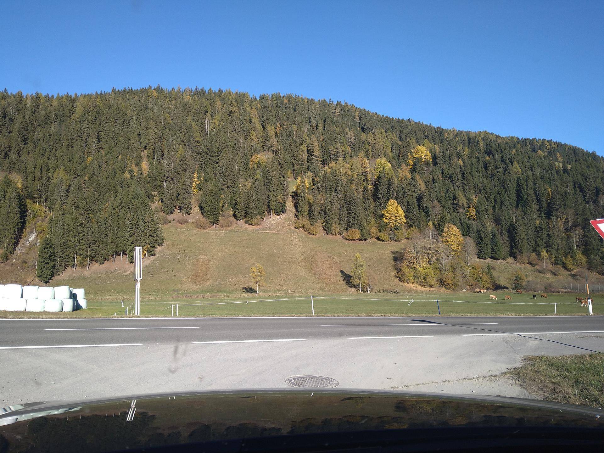 Panoramablick auf die bewaldeten Berge und eine Landstraße unter blauem Himmel.