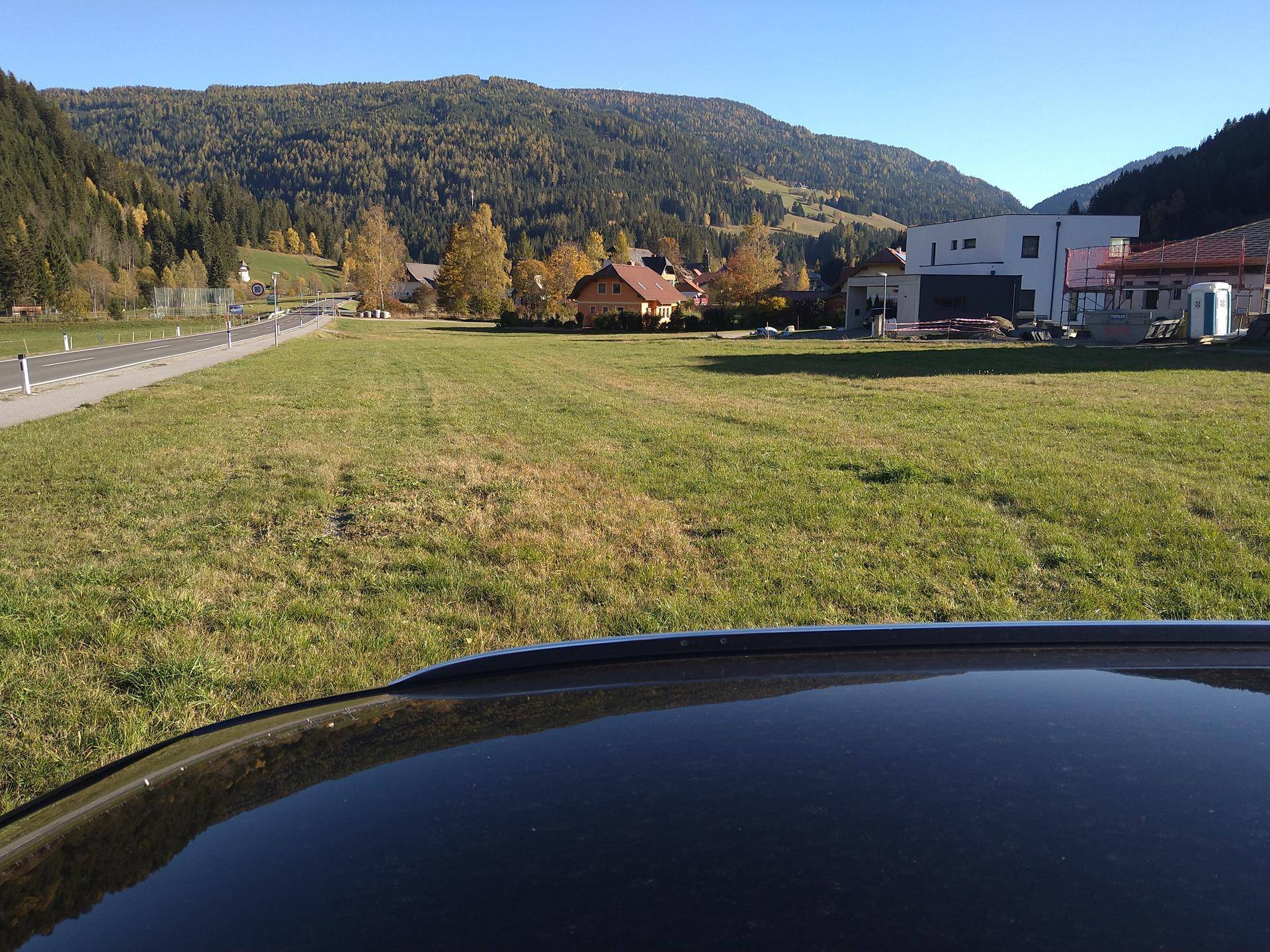 Freies Baugrundstück mit Blick auf die umliegende Bebauung und die herbstliche Bergkulisse.