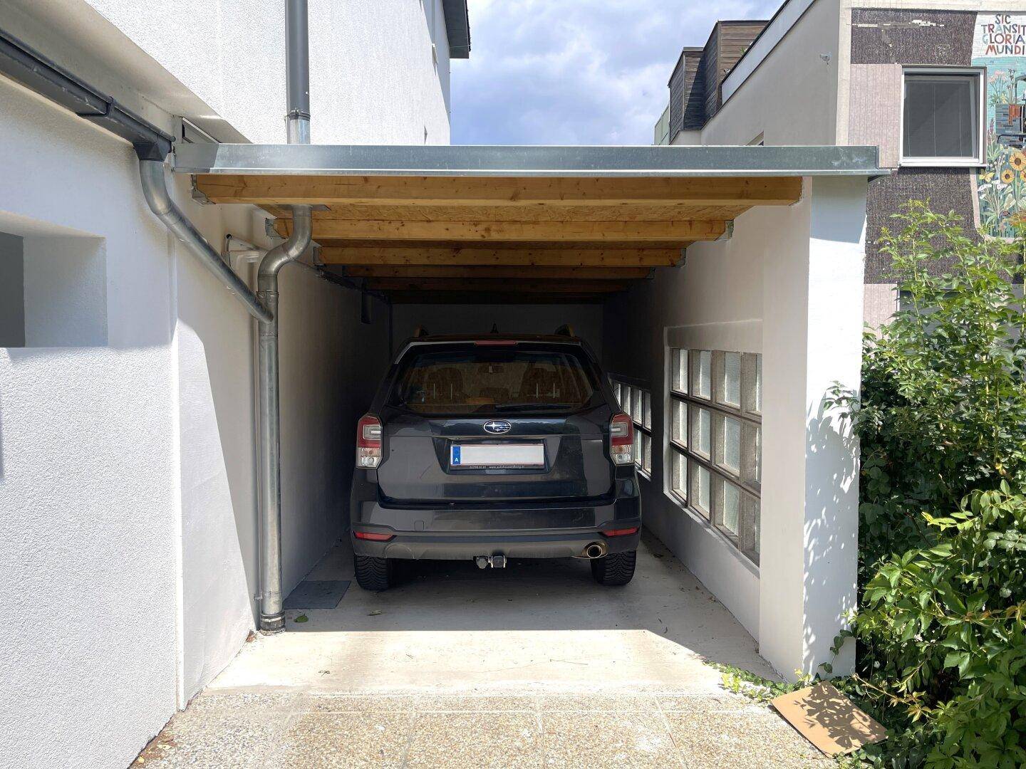 Überdachter Stellplatz oder Carport mit Holzdach und Platz für ein Fahrzeug.