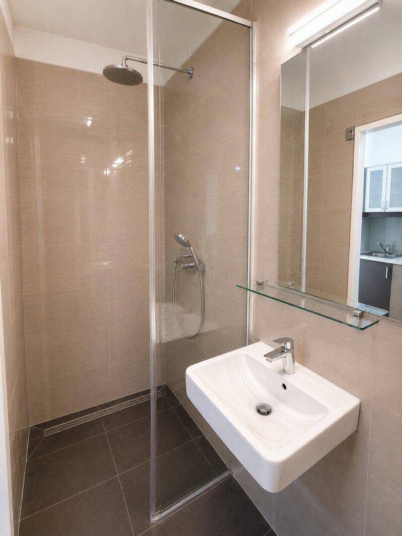 Modernes Badezimmer mit ebenerdiger Dusche, Wandwaschbecken und beigefarbenen Fliesen.