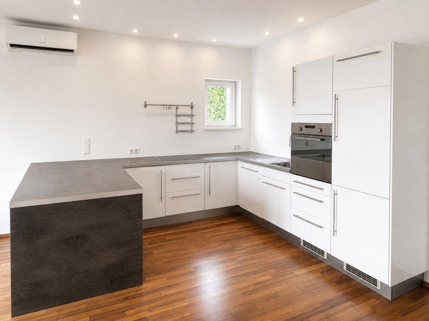 Moderne Einbauküche mit weißen Hochglanzfronten, dunkler Arbeitsplatte und integriertem Backofen.
