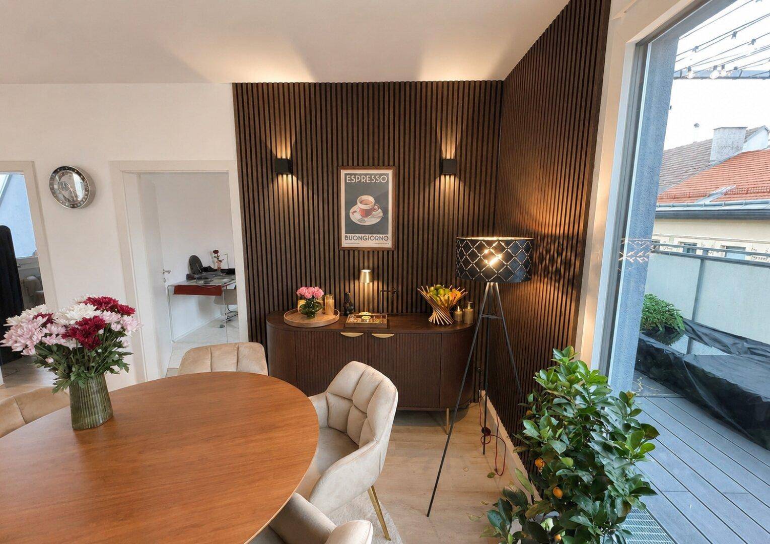 Eleganter Essbereich mit Holzakzentwand, modernem Esstisch und stilvoller Beleuchtung, offen zum Wohnbereich.