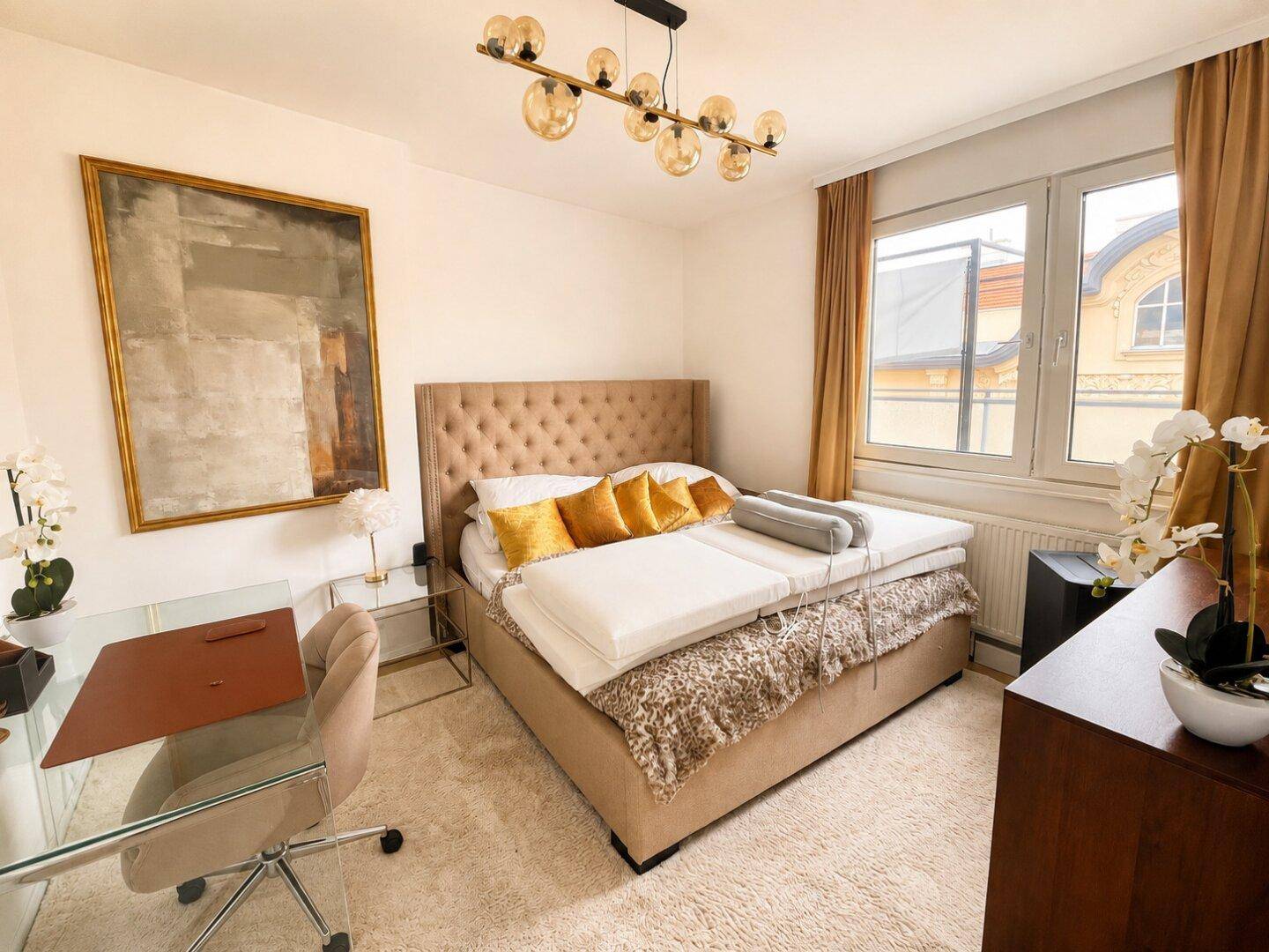 Helles Schlafzimmer mit großem Bett, elegantem Kopfteil, Schreibtisch und Blick nach draußen.