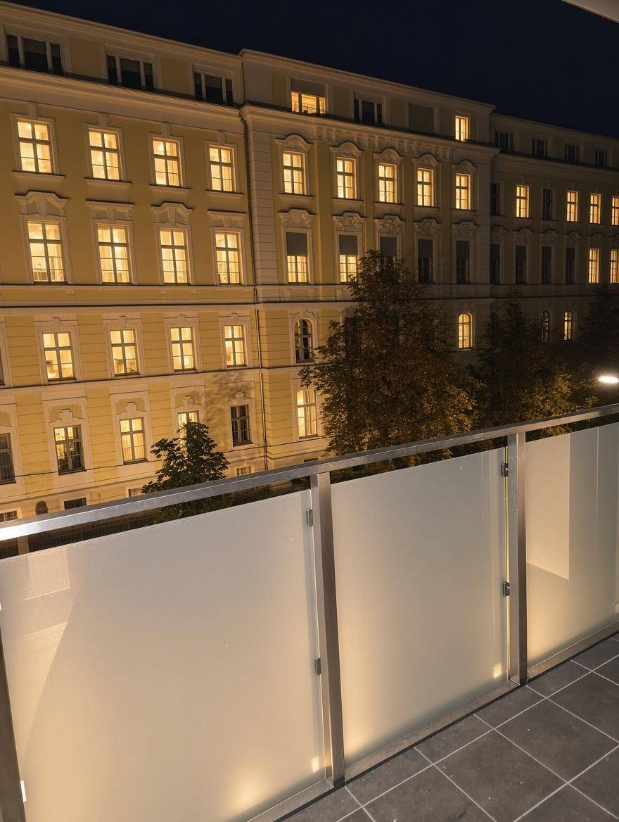Balkon bei Nacht mit Blick auf die beleuchtete Fassade eines Altbaus.