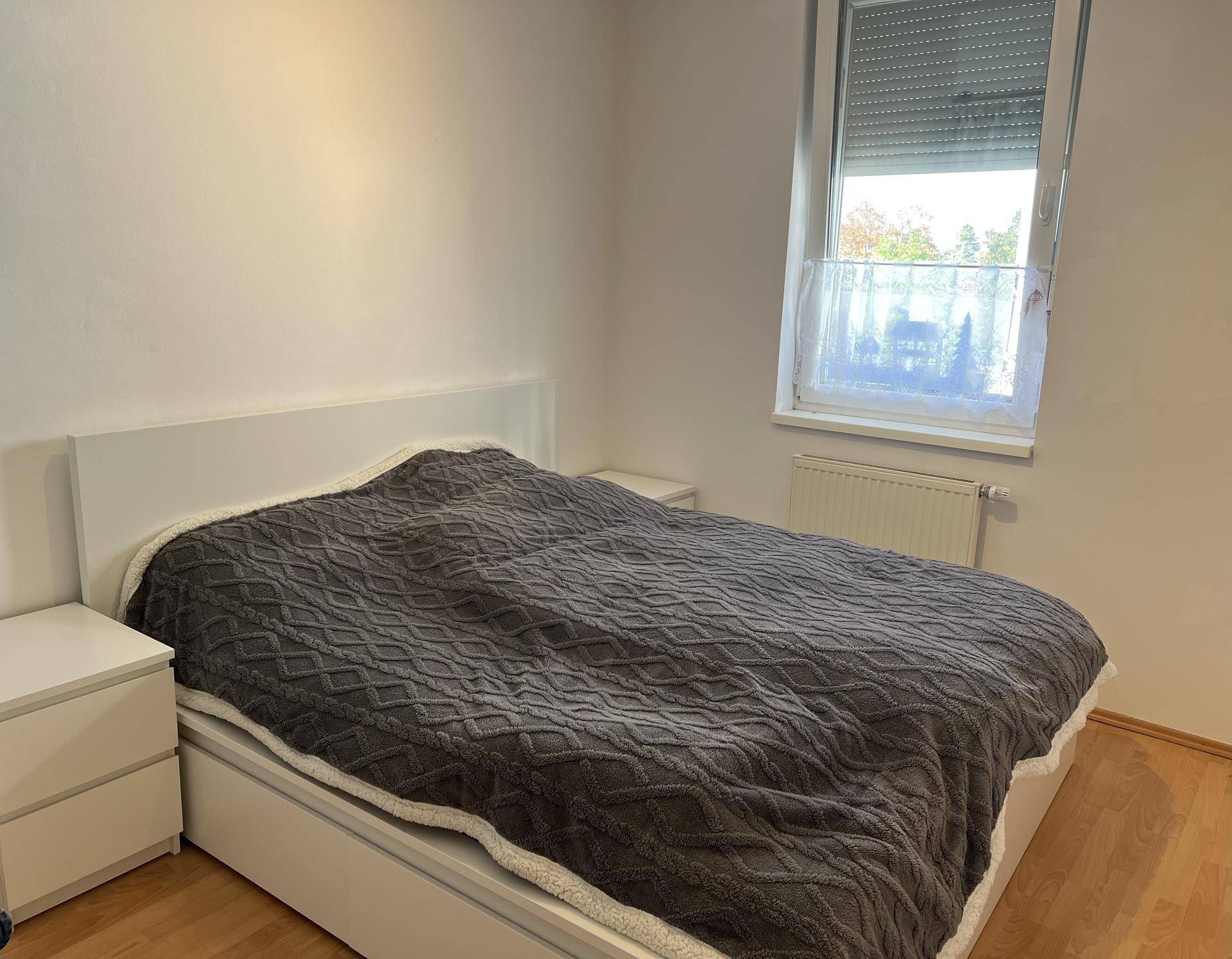 Schlafzimmer mit Doppelbett, Nachttischen und einem Fenster mit Blick nach draußen.