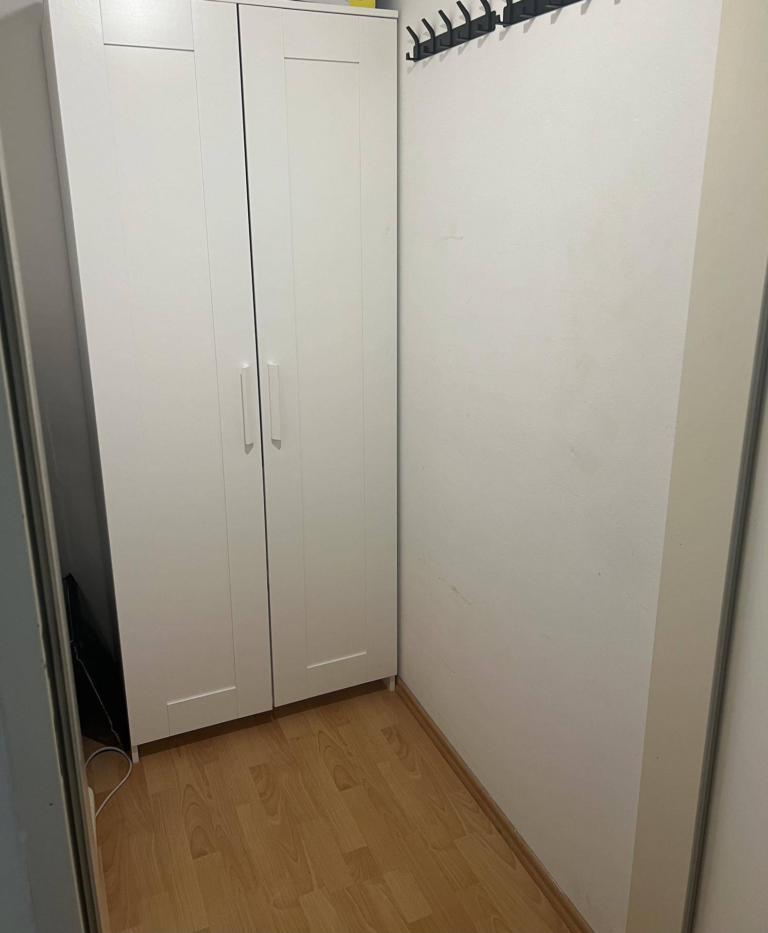 Kleiner Flur mit weißem Kleiderschrank und Garderobenhaken an der Wand.