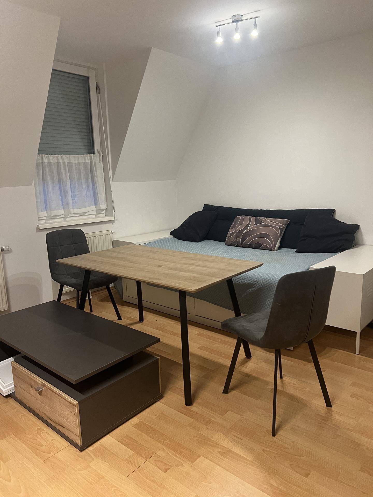 Gemütliches Schlafzimmer im Dachgeschoss mit Schreibtisch, Stühlen und einem Fenster.