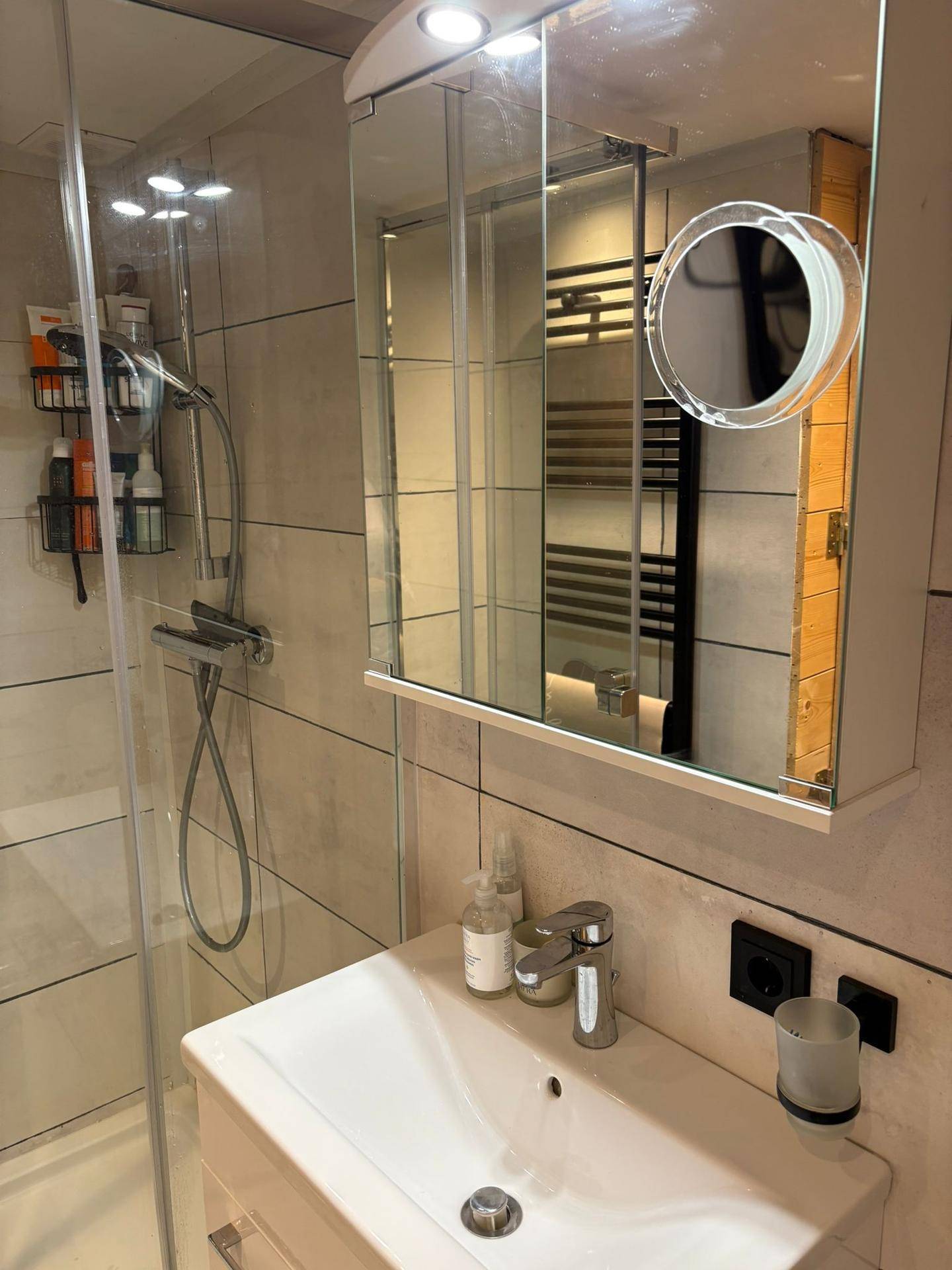 Modernes Badezimmer mit Duschkabine, Waschbecken und Spiegelschrank.