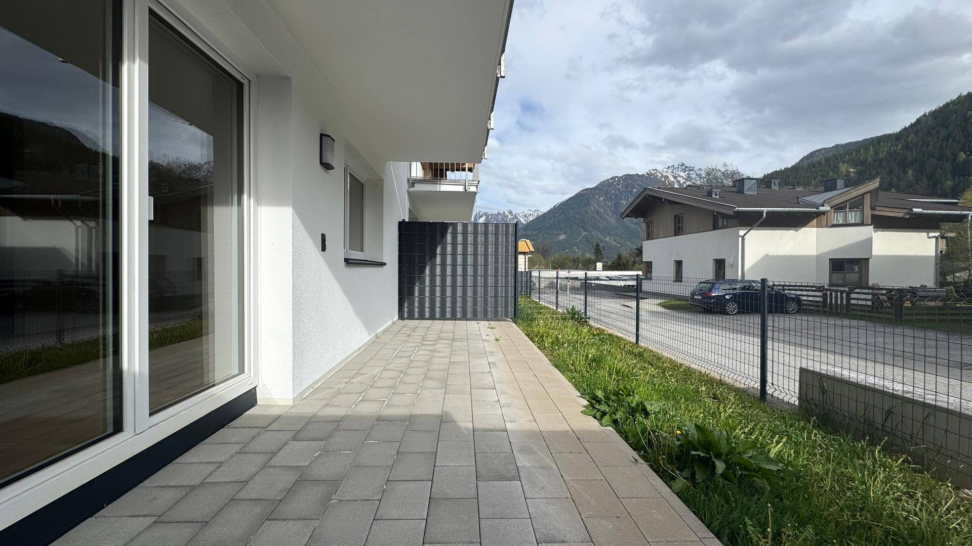 Gepflasterte Terrasse mit Blick auf die Berge und umliegende Häuser, ideal für Entspannung im Freien.