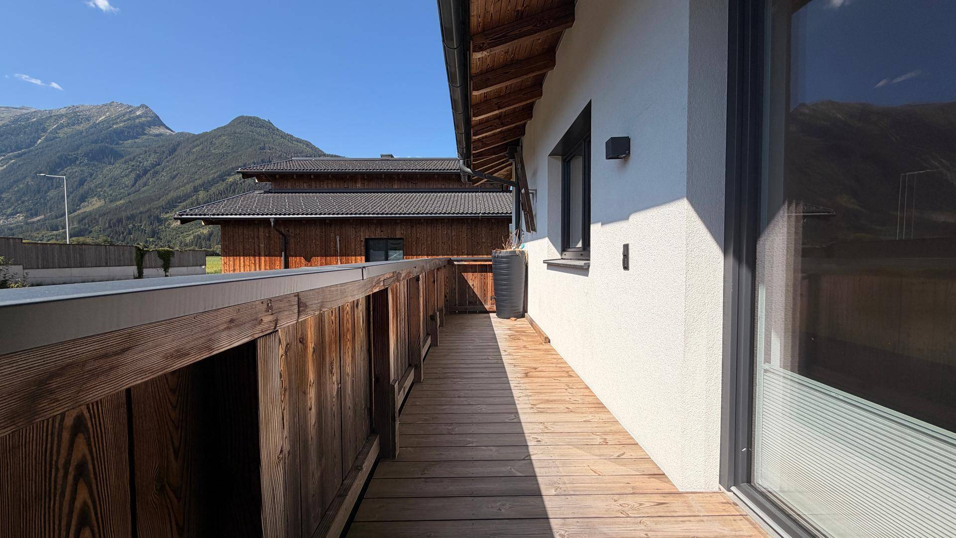 Langer Holzbalkon mit Bergblick und Blick auf die umliegenden Gebäude.