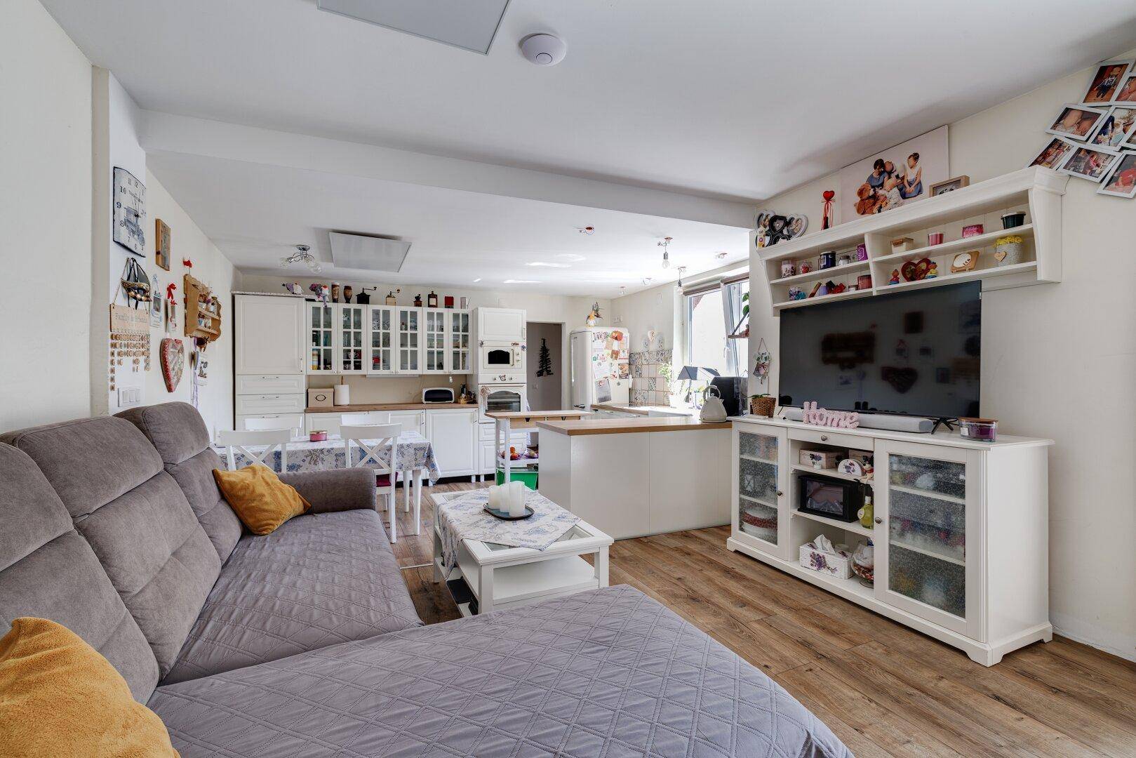 Geräumiger Wohn- und Essbereich mit Sofa, TV-Möbeln und Blick auf die offene Küche.