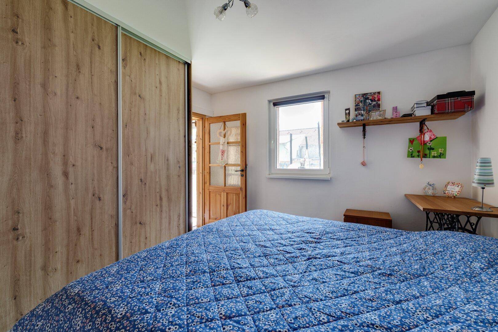 Schlafzimmer mit Fenster, Holzoptikboden und praktischen Einbauschränken.