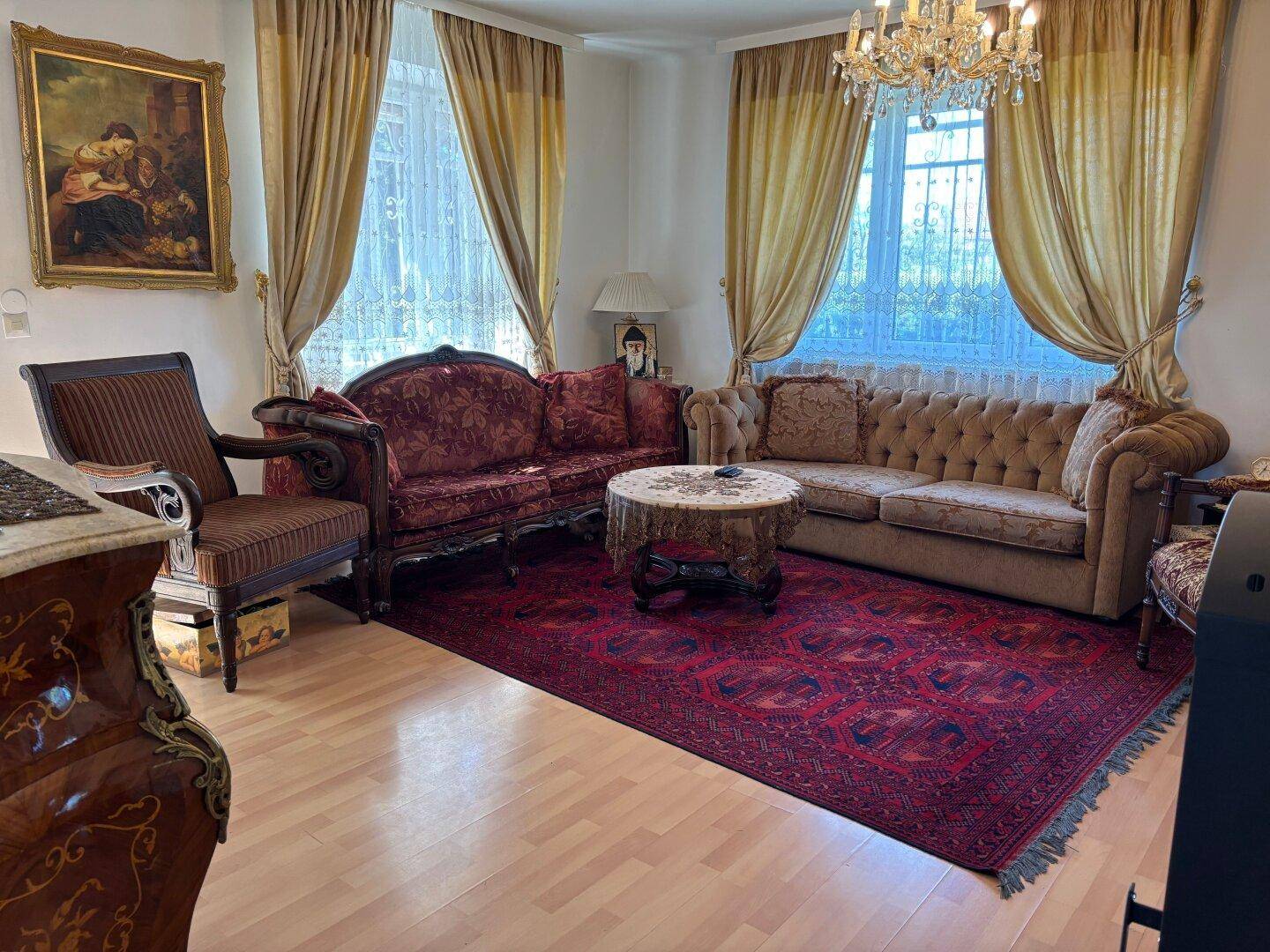 Gemütliches Wohnzimmer mit Holzboden, traditionellen Sofas und einem großen Teppich.