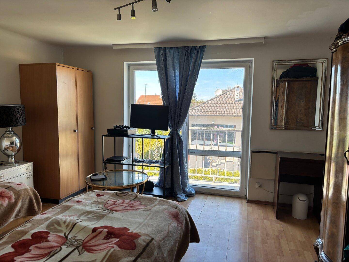 Schlafzimmer mit Holzboden, großem Fenster und Blick auf die Umgebung.
