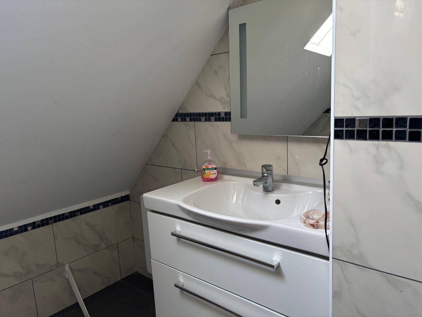 Modernes Badezimmer im Dachgeschoss mit Waschbecken, Spiegelschrank und Dachschräge.