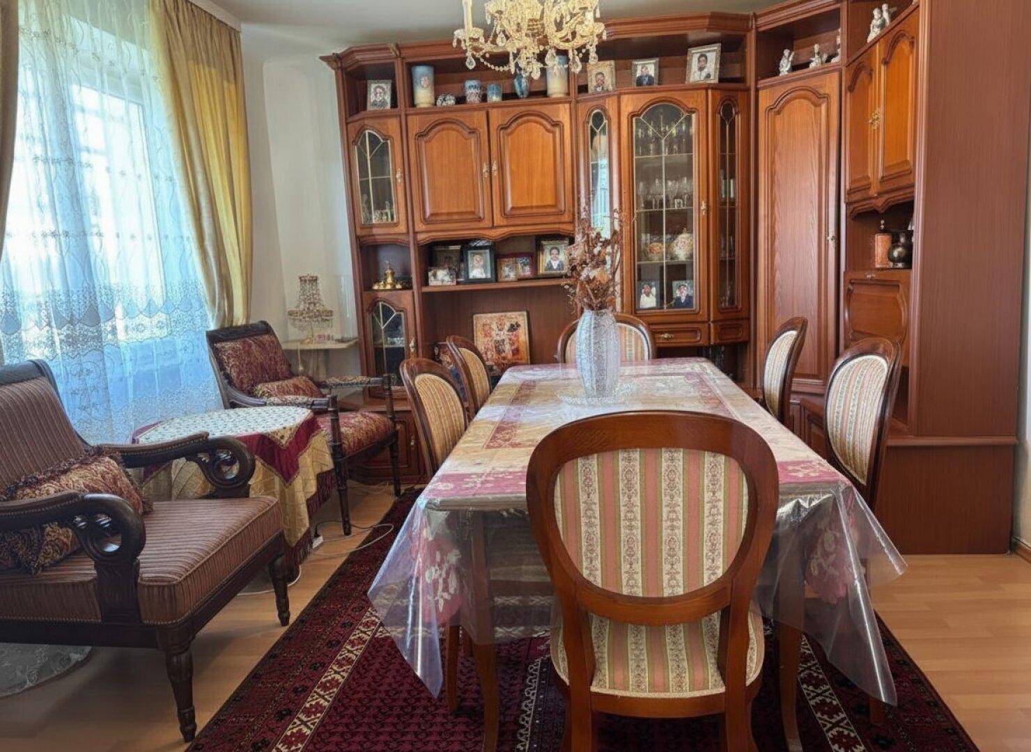 Gemütlicher Wohn- und Essbereich mit klassischen Holzmöbeln und einem eleganten Kronleuchter.