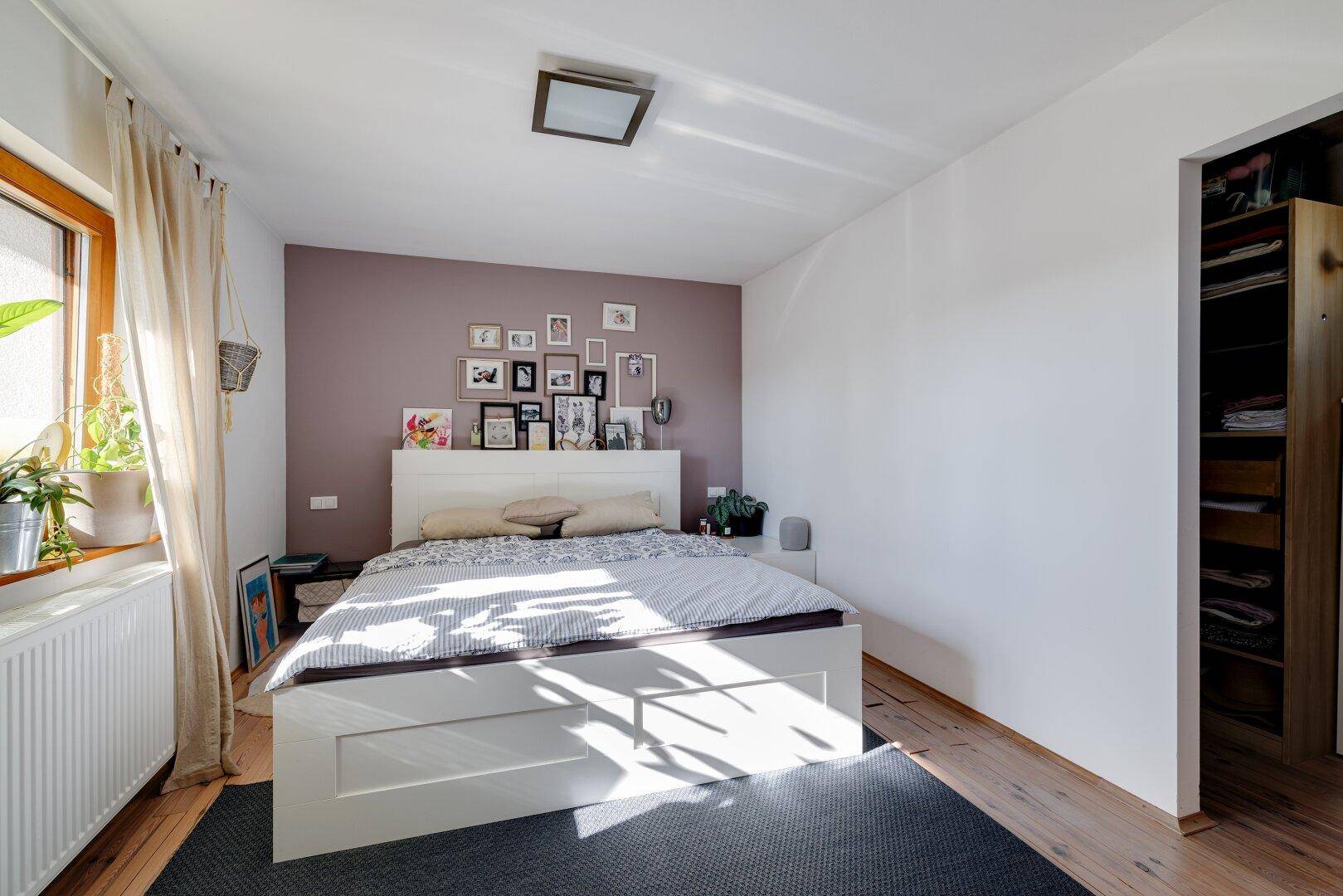 Helles Schlafzimmer mit Holzboden, großem Bett und integriertem Kleiderschrankbereich.