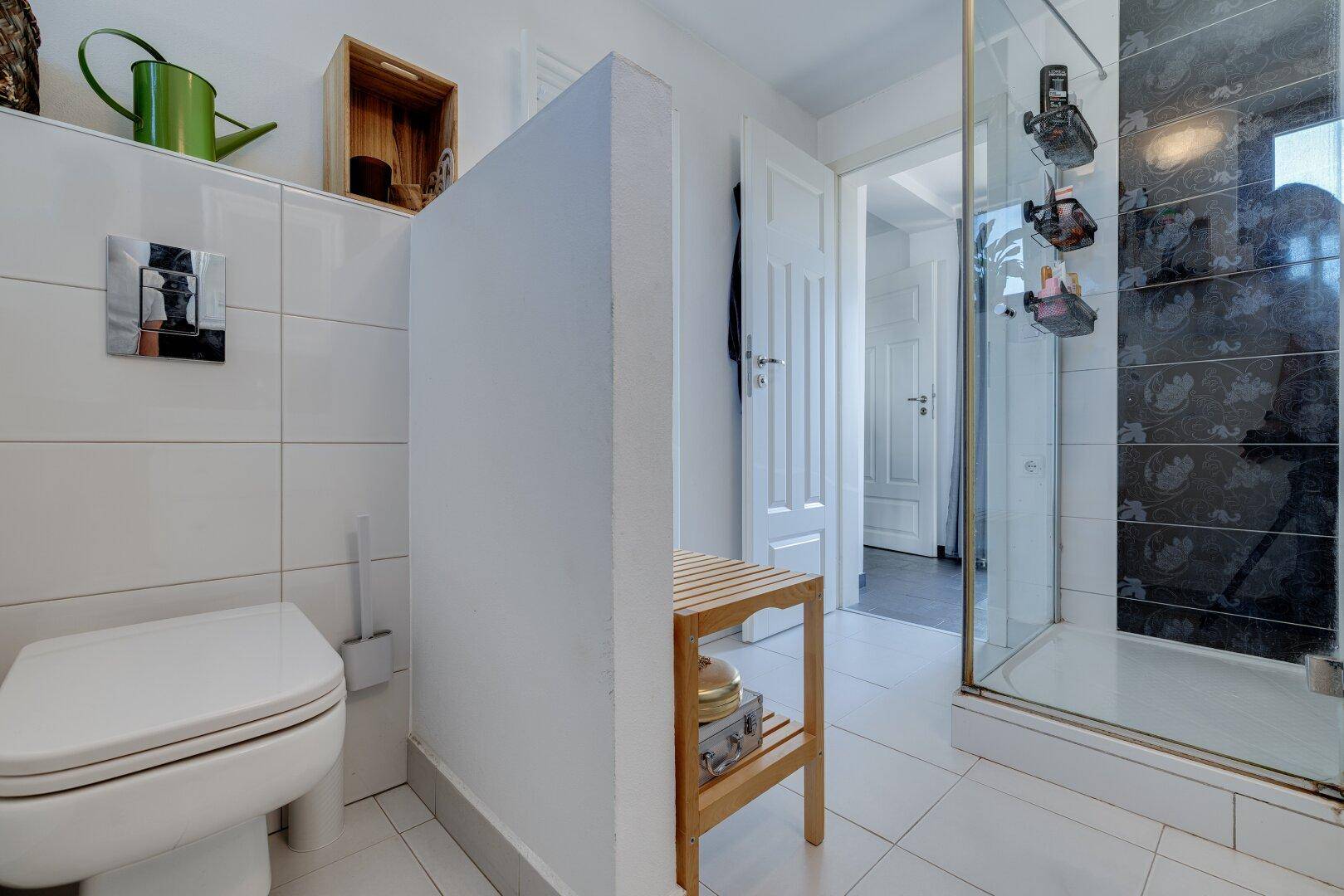 Helles Badezimmer mit WC, Duschkabine und modernen Fliesen in Schwarz-Weiß.