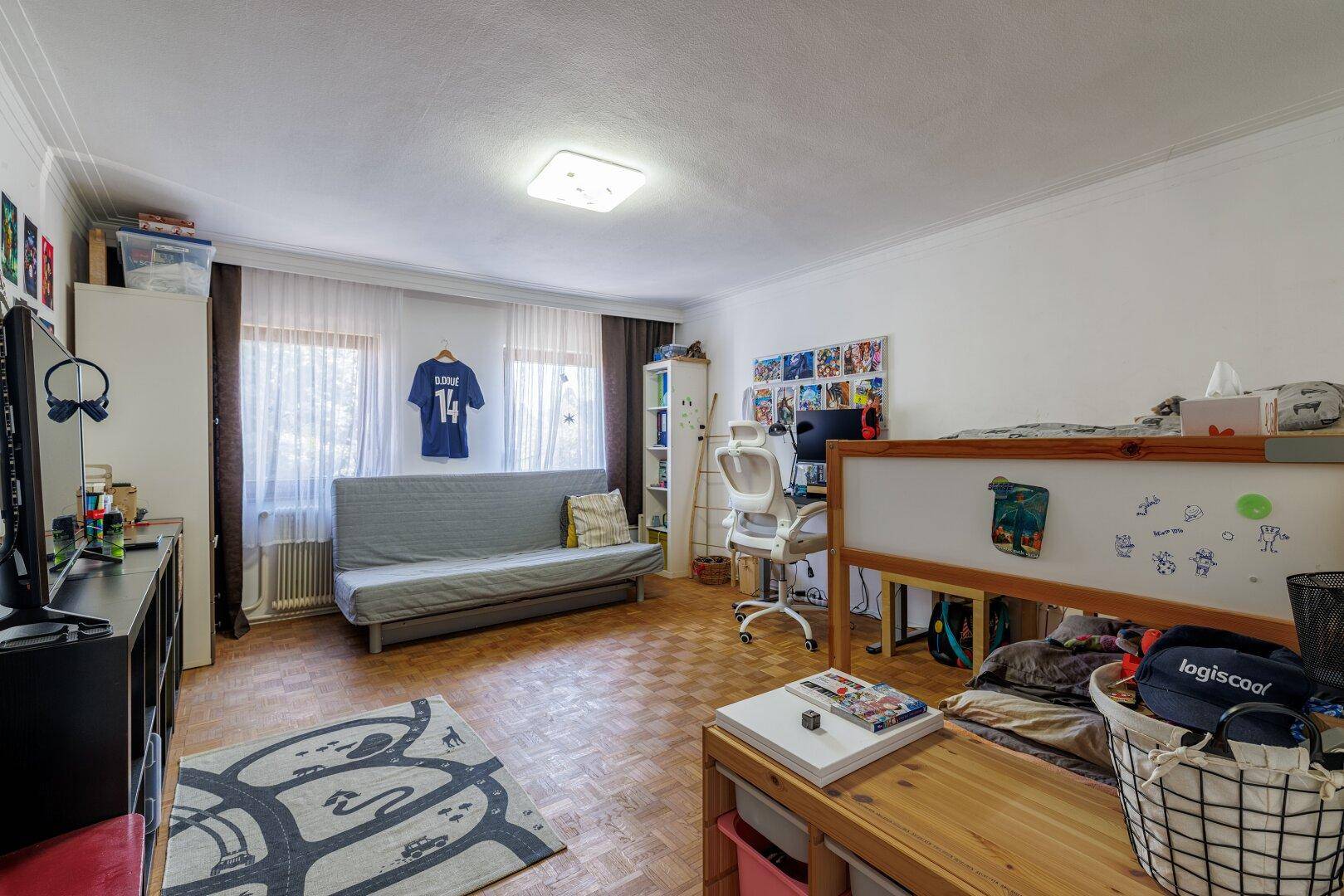 Geräumiges Kinderzimmer mit Schlafsofa, Hochbett und Parkettboden.
