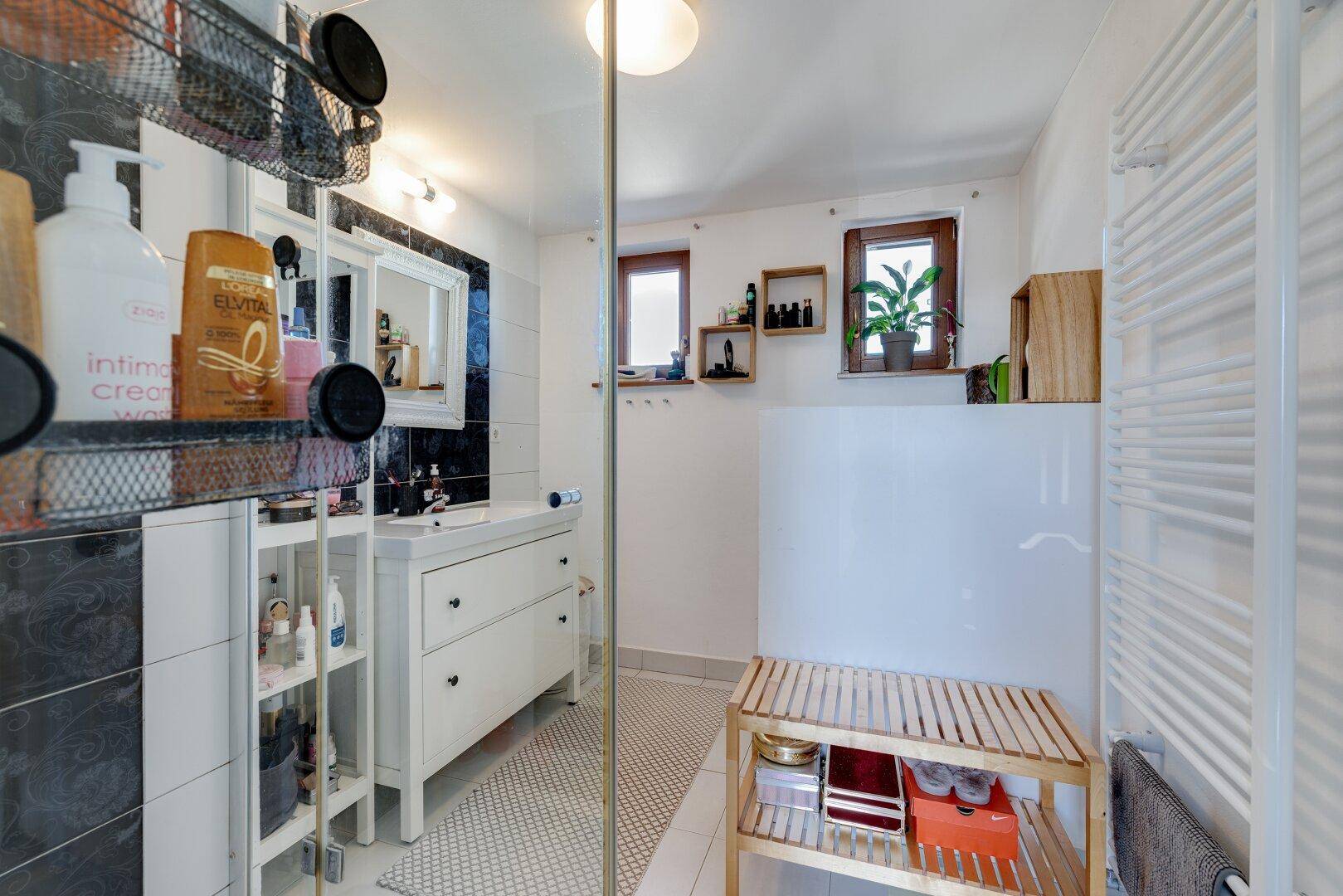 Modernes Badezimmer mit Dusche, Waschtisch und Fenster für natürliche Belüftung.
