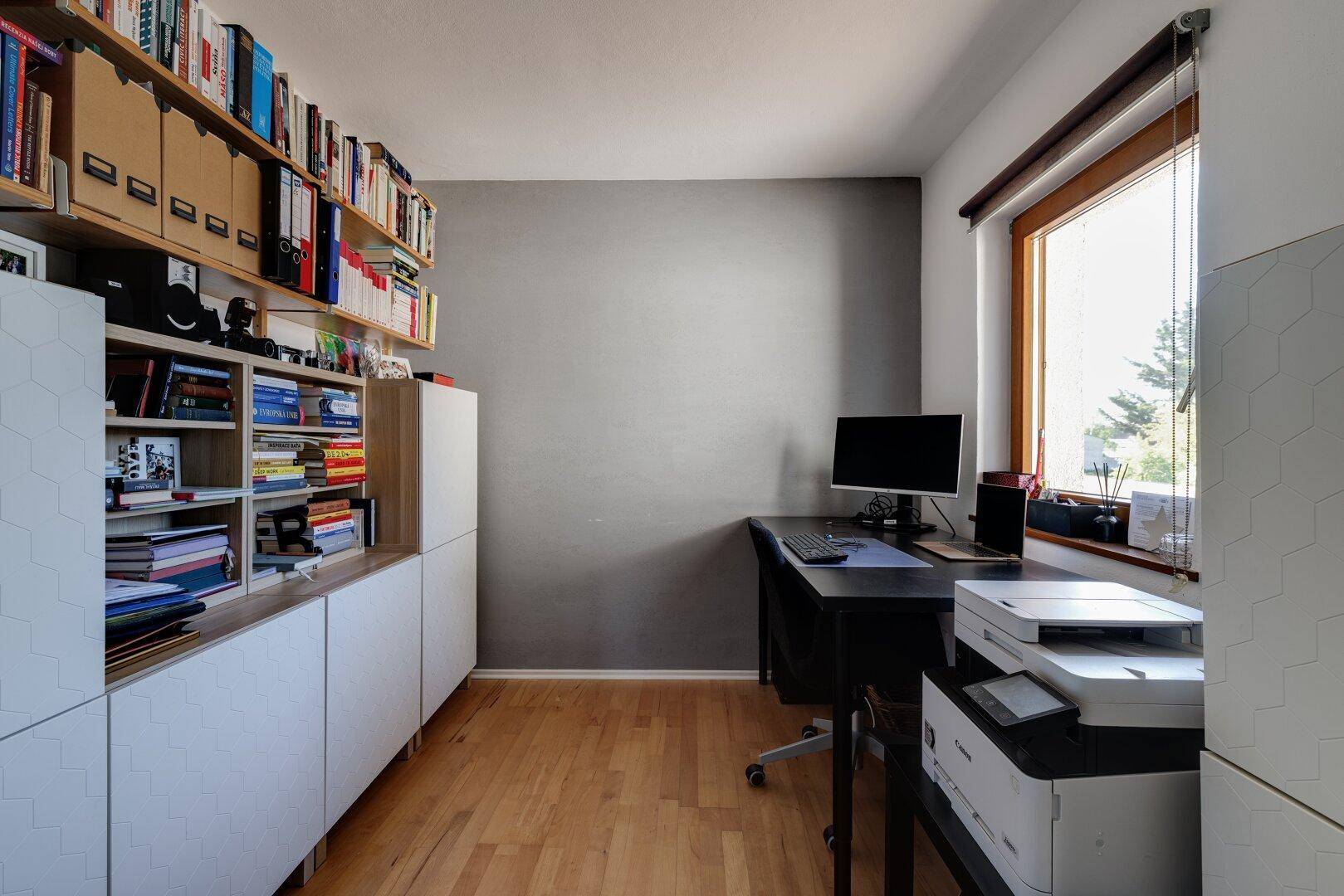 Funktionales Arbeitszimmer mit Schreibtisch, Regalen und Holzboden.