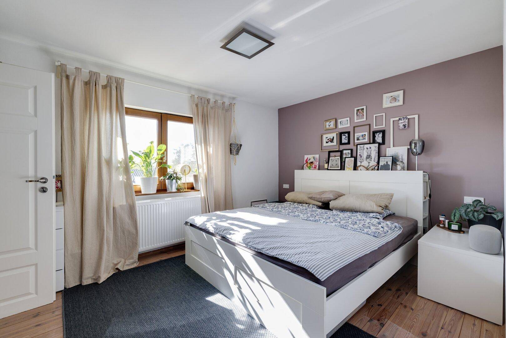 Gemütliches Schlafzimmer mit Doppelbett, Holzboden und farbiger Akzentwand.