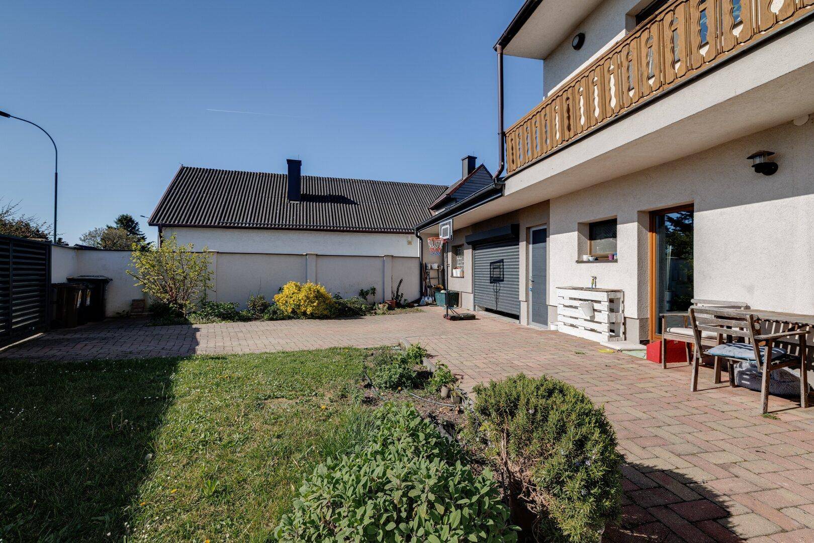 Außenbereich des Hauses mit gepflastertem Hof, Garage und Gartenanteil.