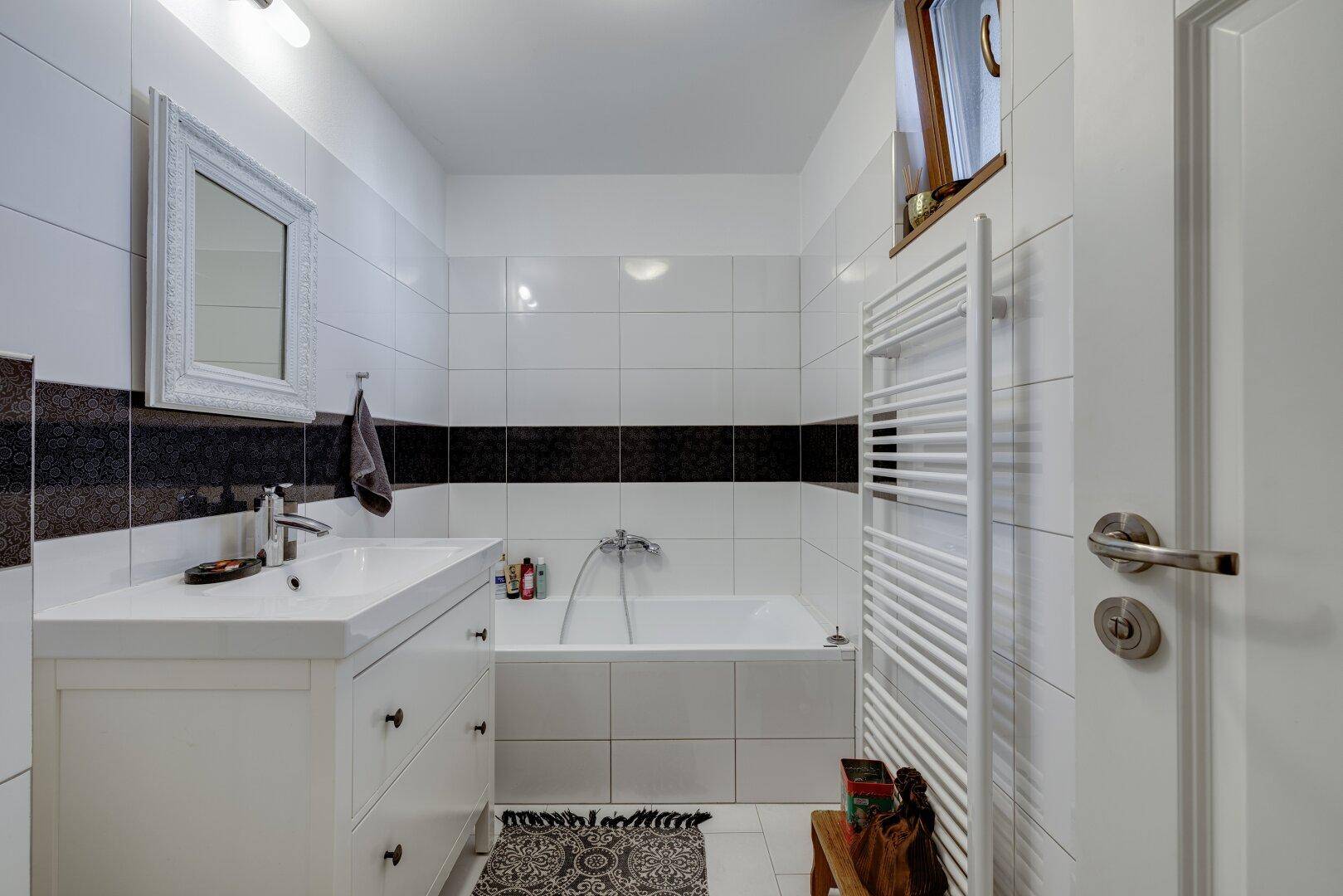 Modernes Badezimmer mit Badewanne, Waschtisch und beheiztem Handtuchhalter.