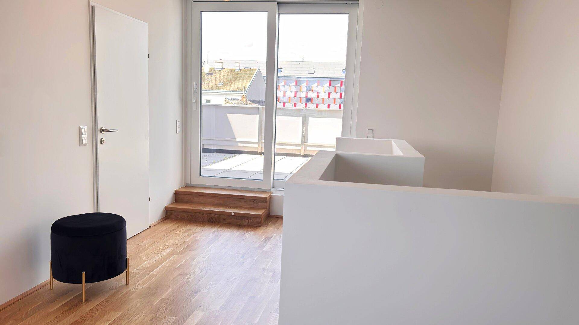 Heller Flurbereich im Obergeschoss mit Holzboden und Zugang zu einer Dachterrasse.