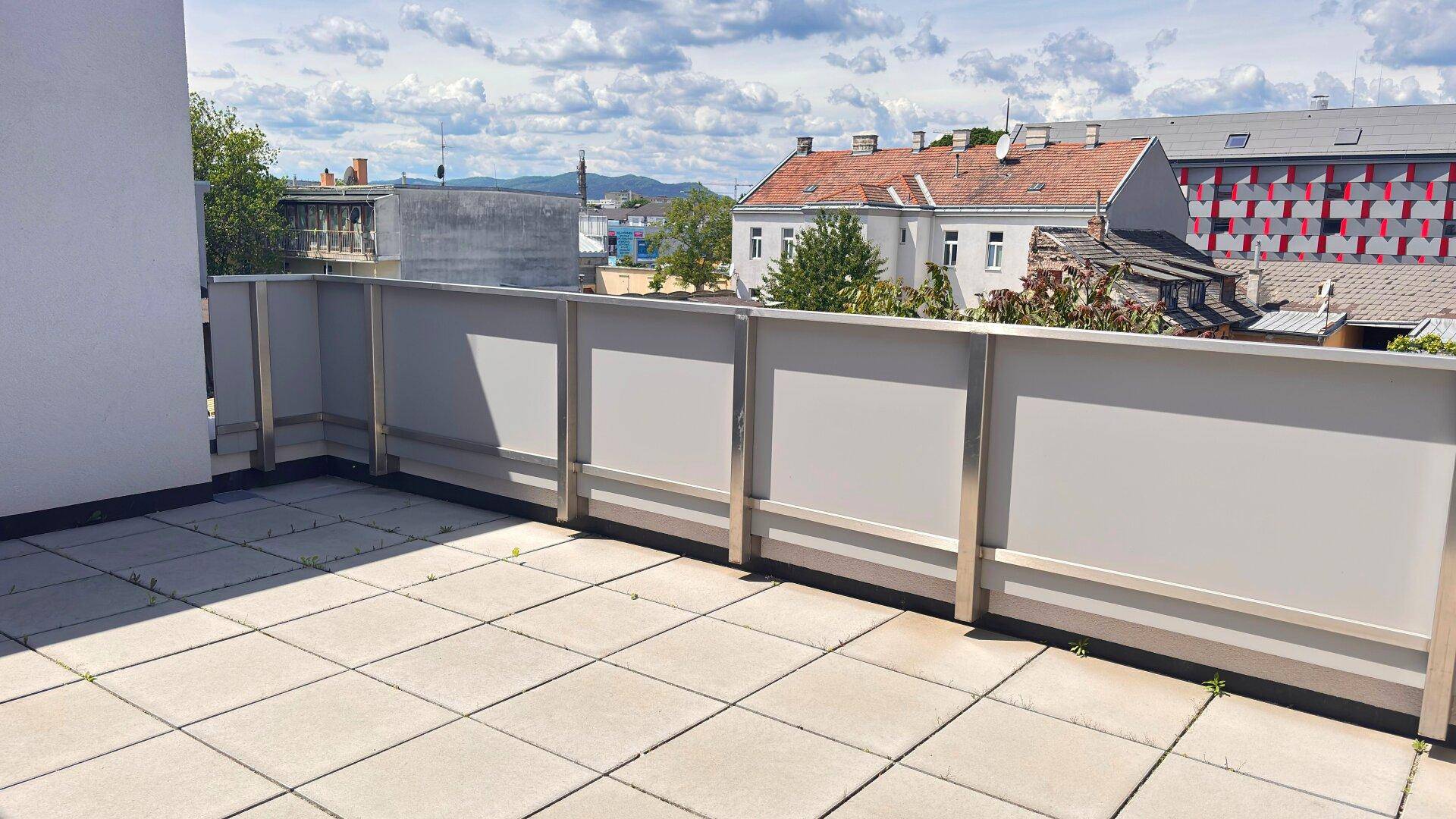 Weitläufige Dachterrasse mit Fliesen und Panoramablick über die städtische Umgebung.