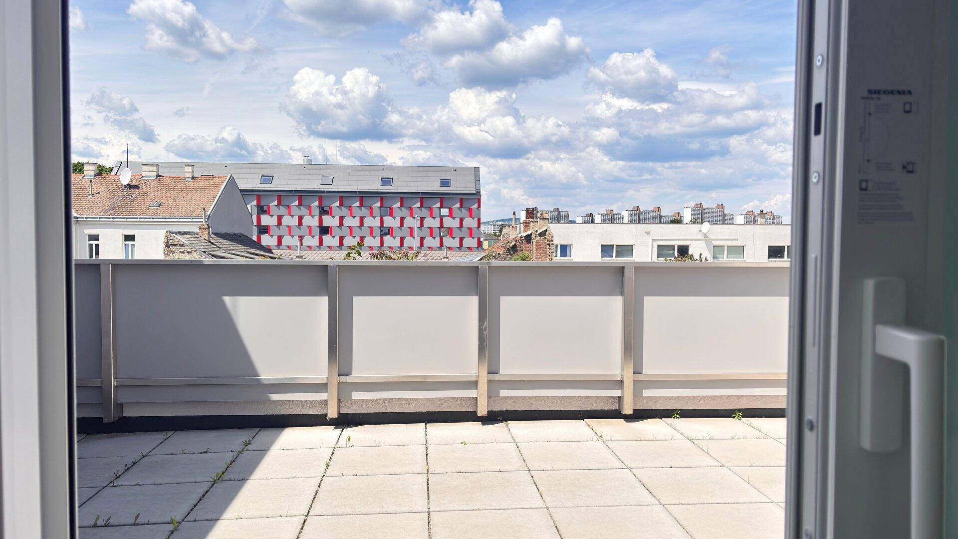 Geräumige Terrasse mit Fliesenboden und Blick auf die umliegenden Gebäude der Stadt.