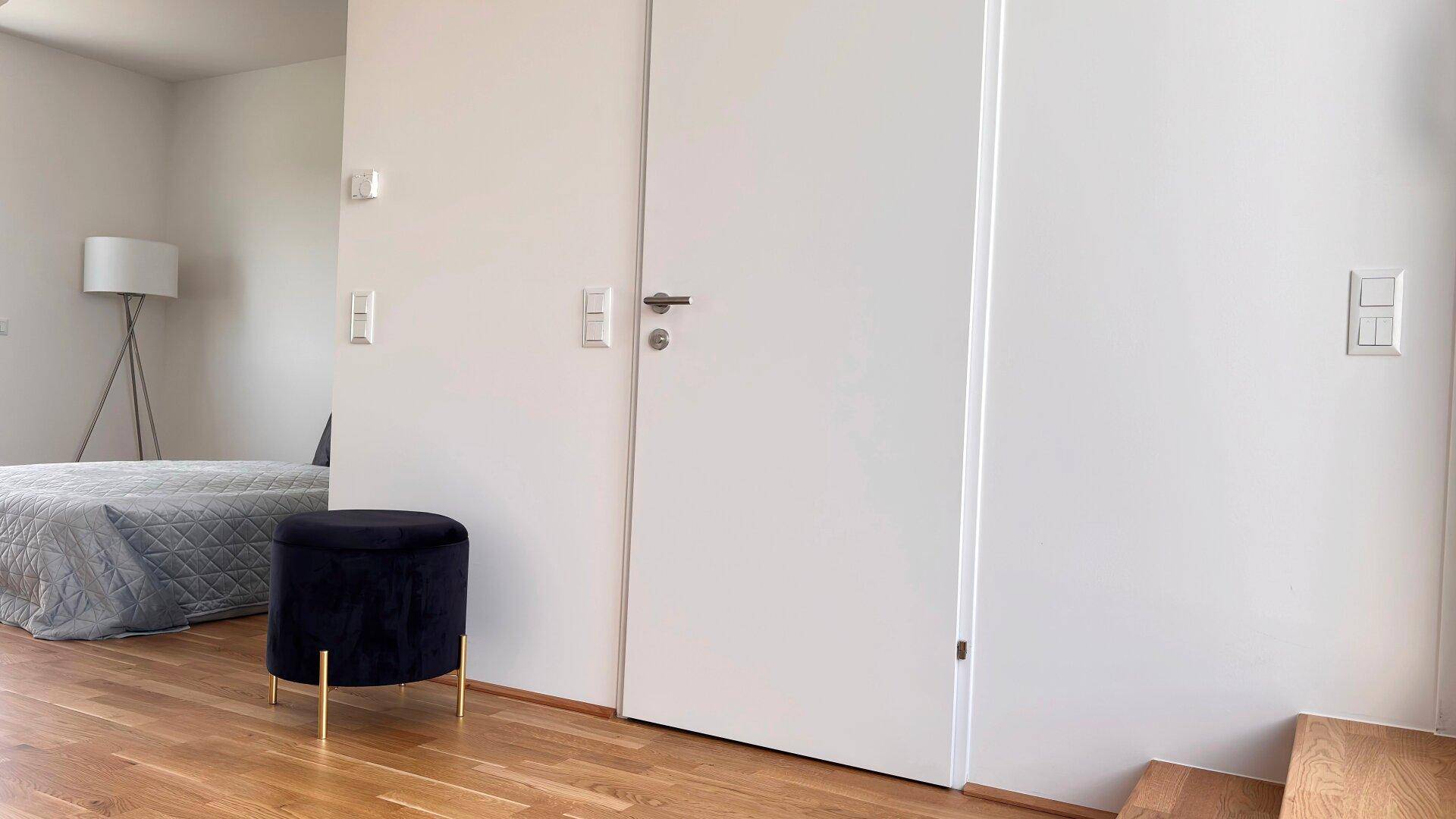 Heller Innenraum mit Holzboden und moderner Einrichtung, angrenzend an den Schlafbereich.
