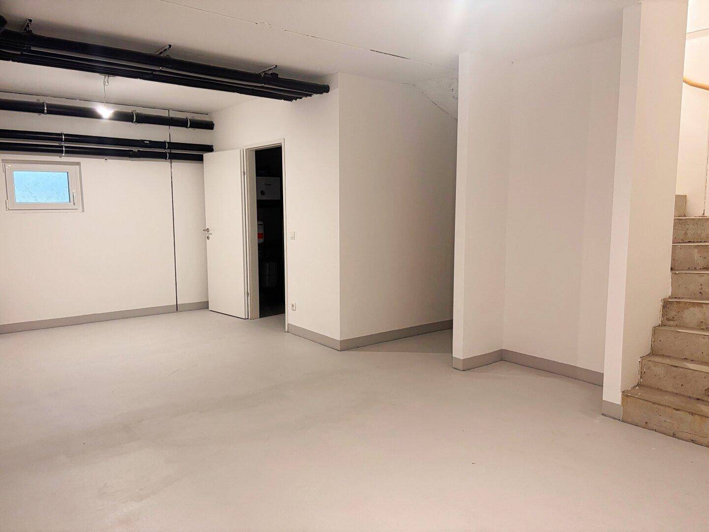 Geräumiger Kellerraum mit Betonboden und sichtbaren Installationen, ideal als Lagerfläche.