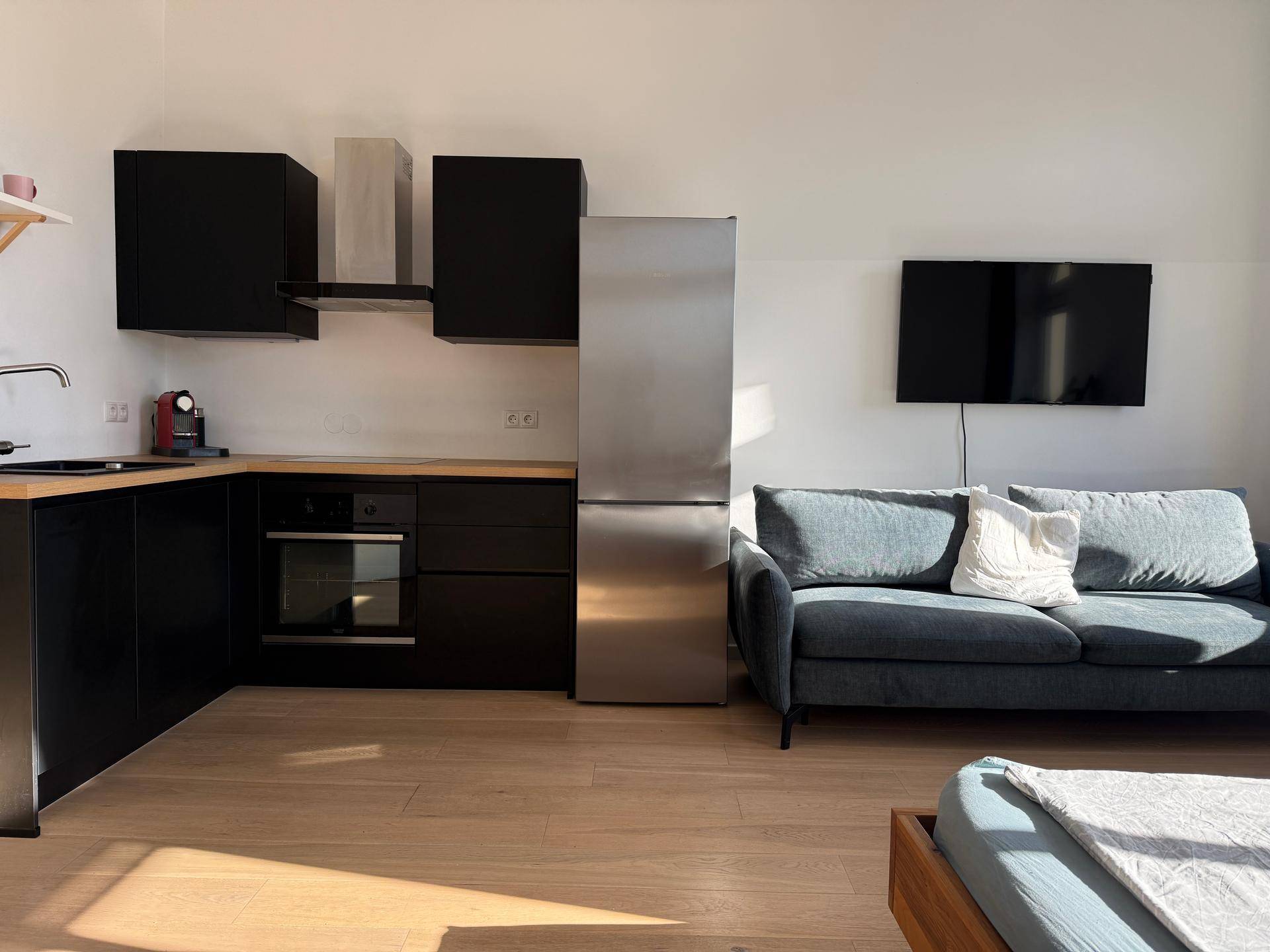 Moderne Küchenzeile mit schwarzen Schränken, Holz-Arbeitsplatte und integrierten Geräten im offenen Wohnbereich.