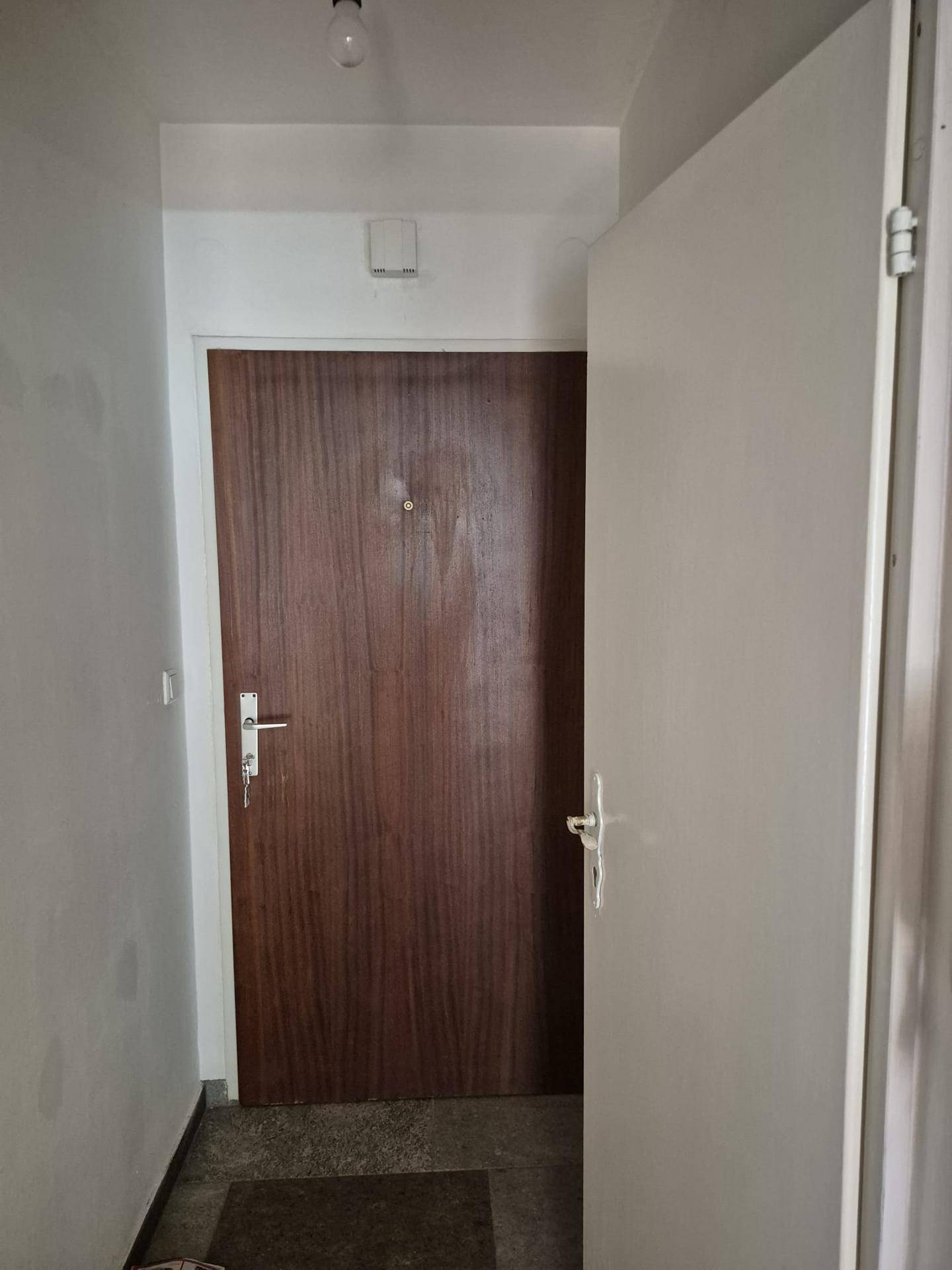 Eingangsbereich mit dunkler Holztür und Fliesenboden.