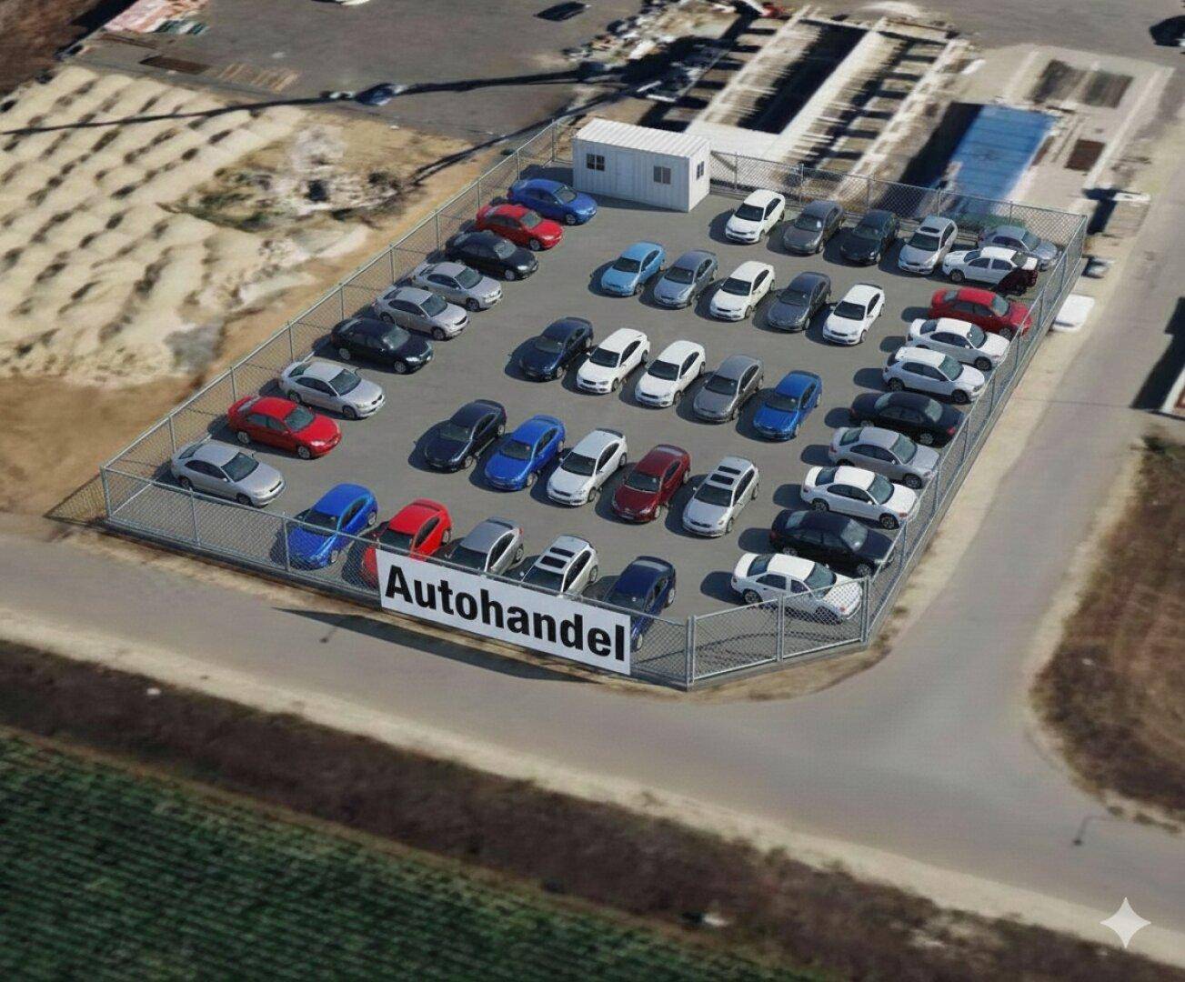 Luftaufnahme eines eingezäunten Autohandels mit zahlreichen Gebrauchtwagen auf einer betonierten Fläche.