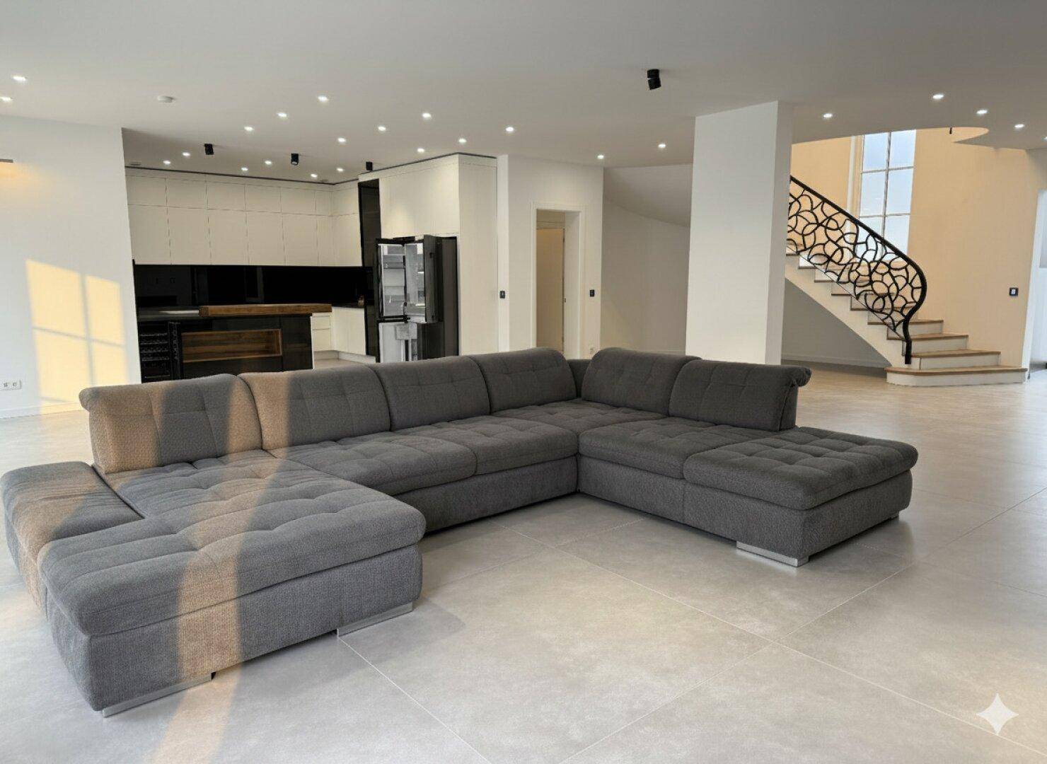 Geräumiges Wohnzimmer mit großem Ecksofa, integrierter Beleuchtung und offener Gestaltung.