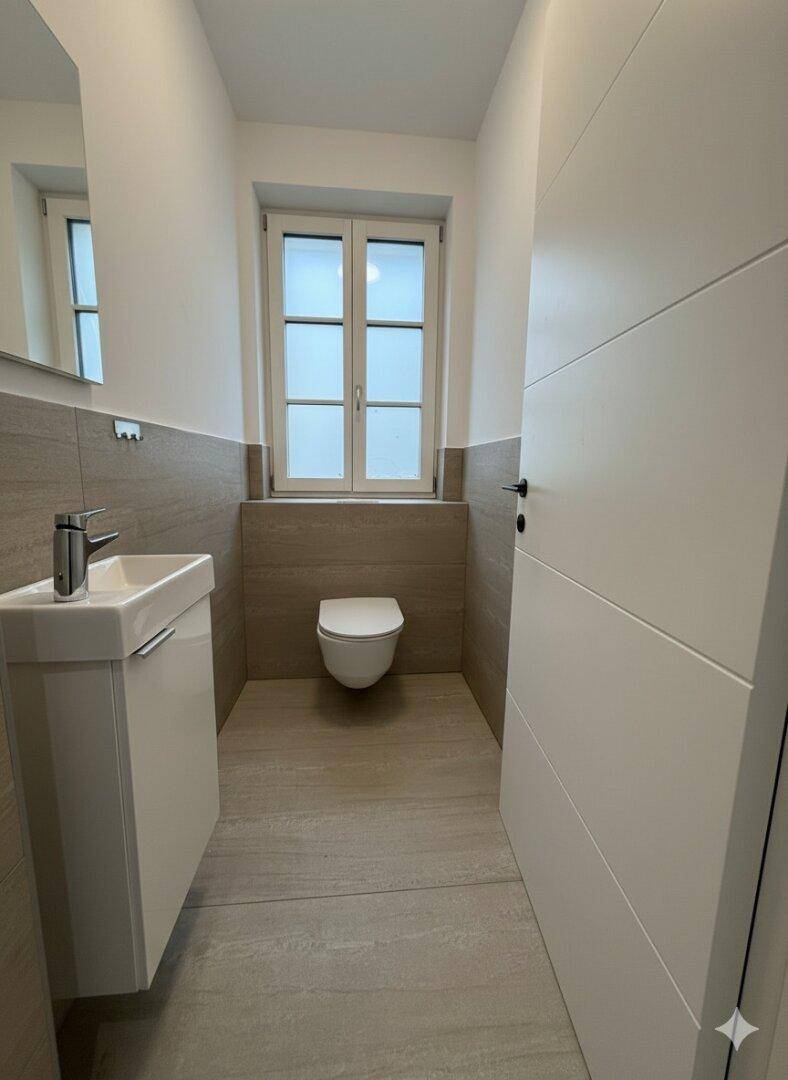 Modernes Gäste-WC mit wandhängender Toilette, kleinem Waschbecken und Fenster.