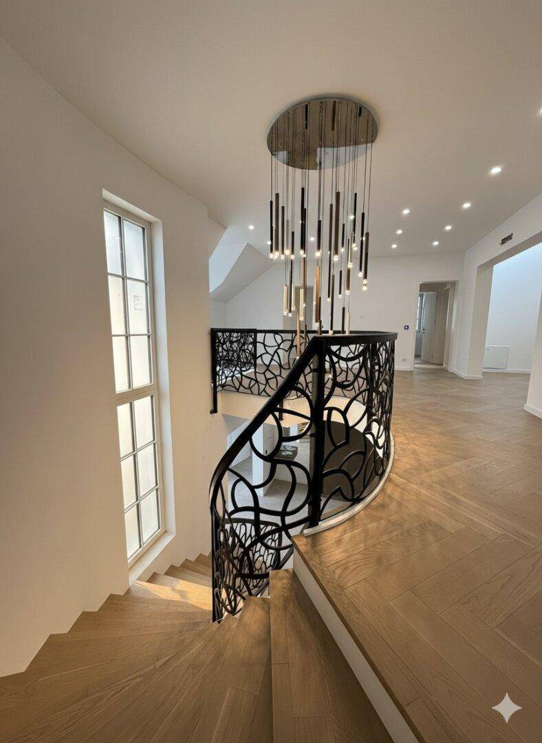 Heller Treppenabsatz im Obergeschoss mit großen Fenstern und elegantem Fischgrätparkett.