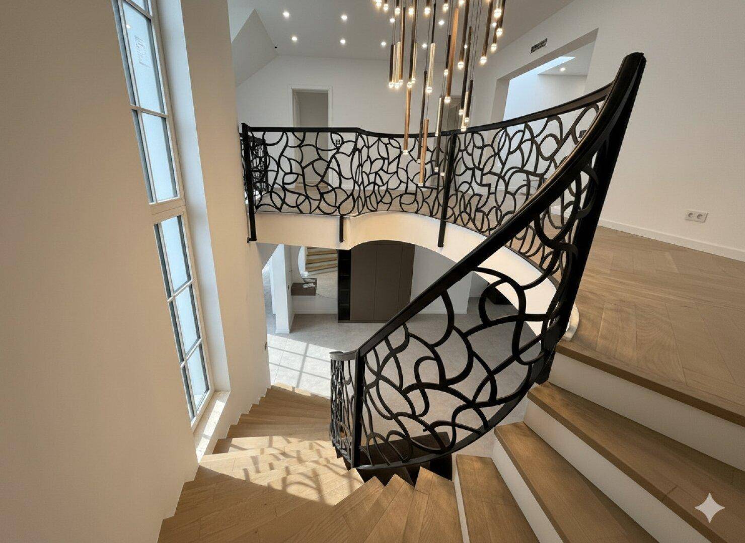 Elegante Treppe mit kunstvollem Geländer führt zum oberen Stockwerk mit Parkettboden.