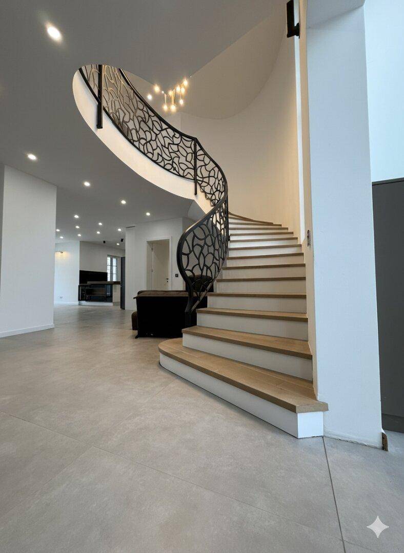 Großzügiger Flur mit geschwungener Treppe und modernem Geländer, offen zum Wohnbereich.